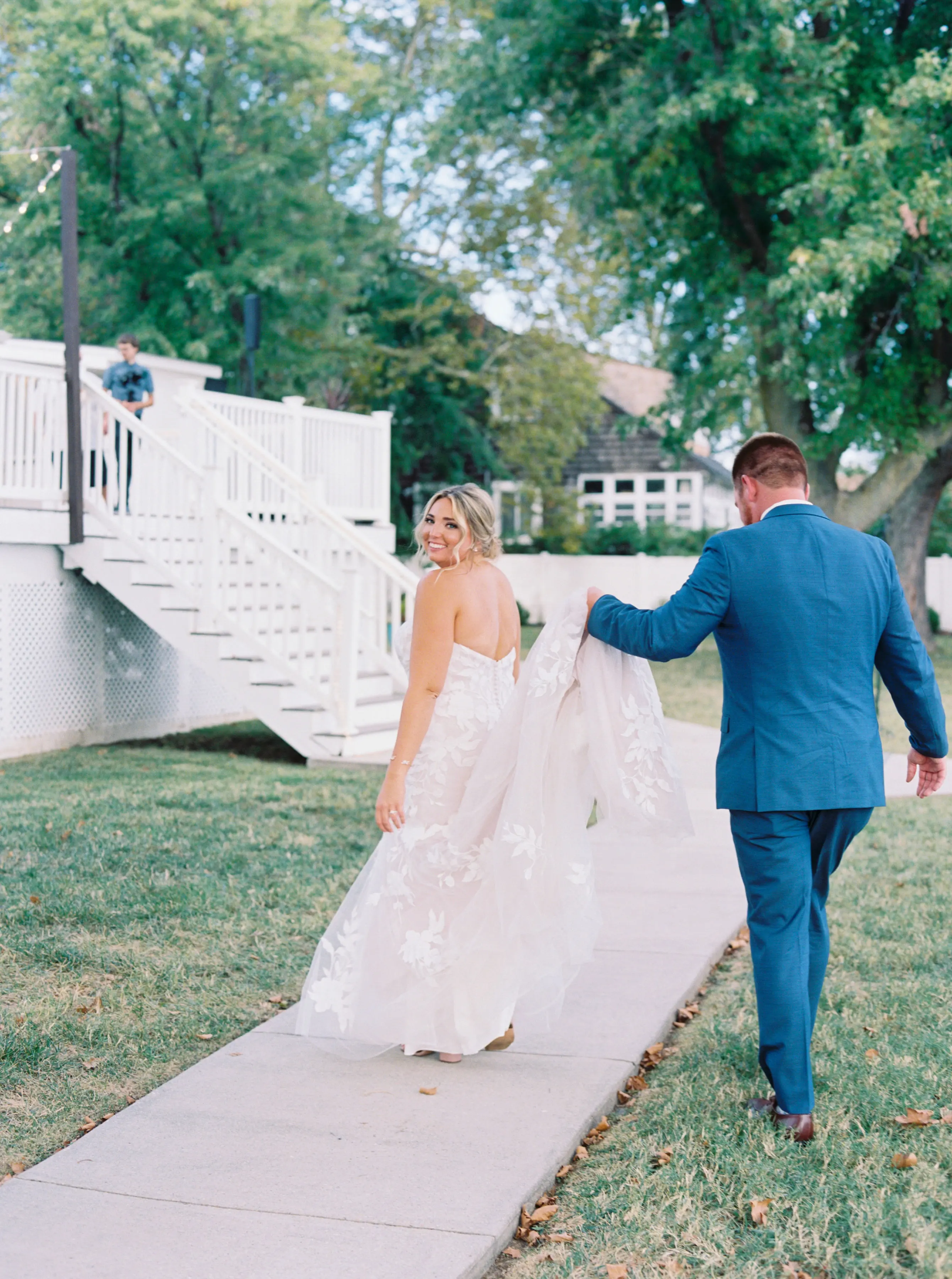 Bride Wearing Lace Mermaid Wedding Gown Called Hattie By Rebecca Ingram With Groom Carrying The Train