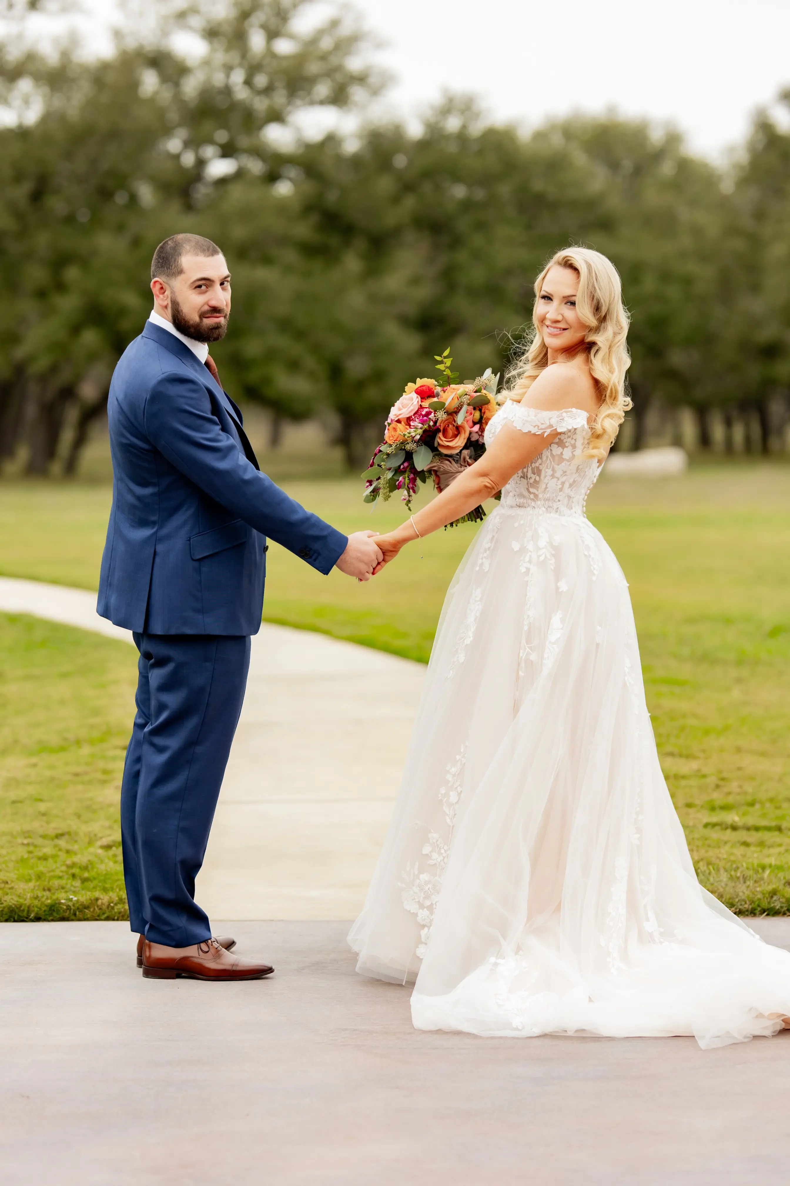 Bride wearing Harlem by Maggie Sottero holding hands with her husband