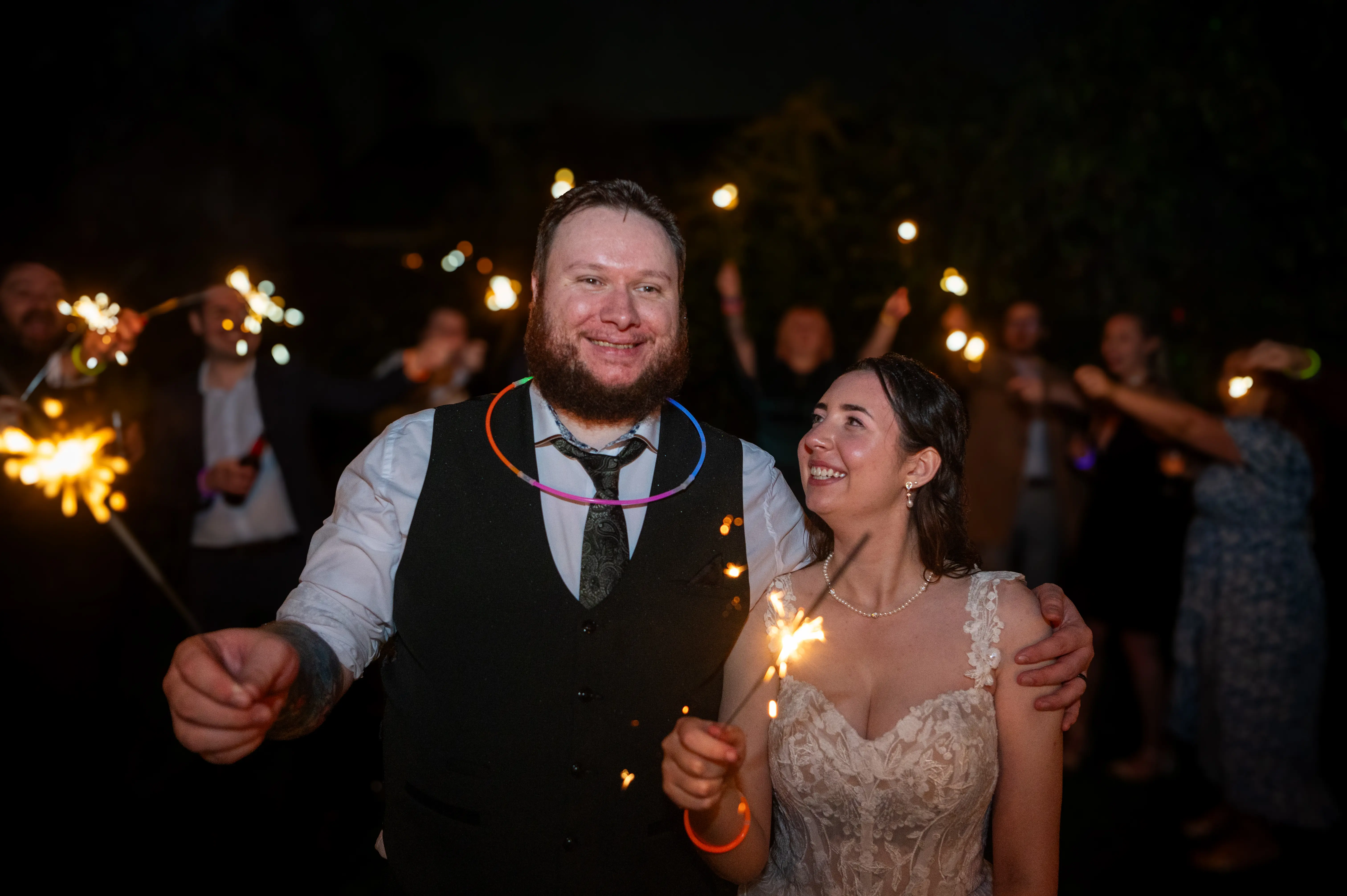 Bride wearing Harlem by Maggie Sottero holding sparklers with her husband