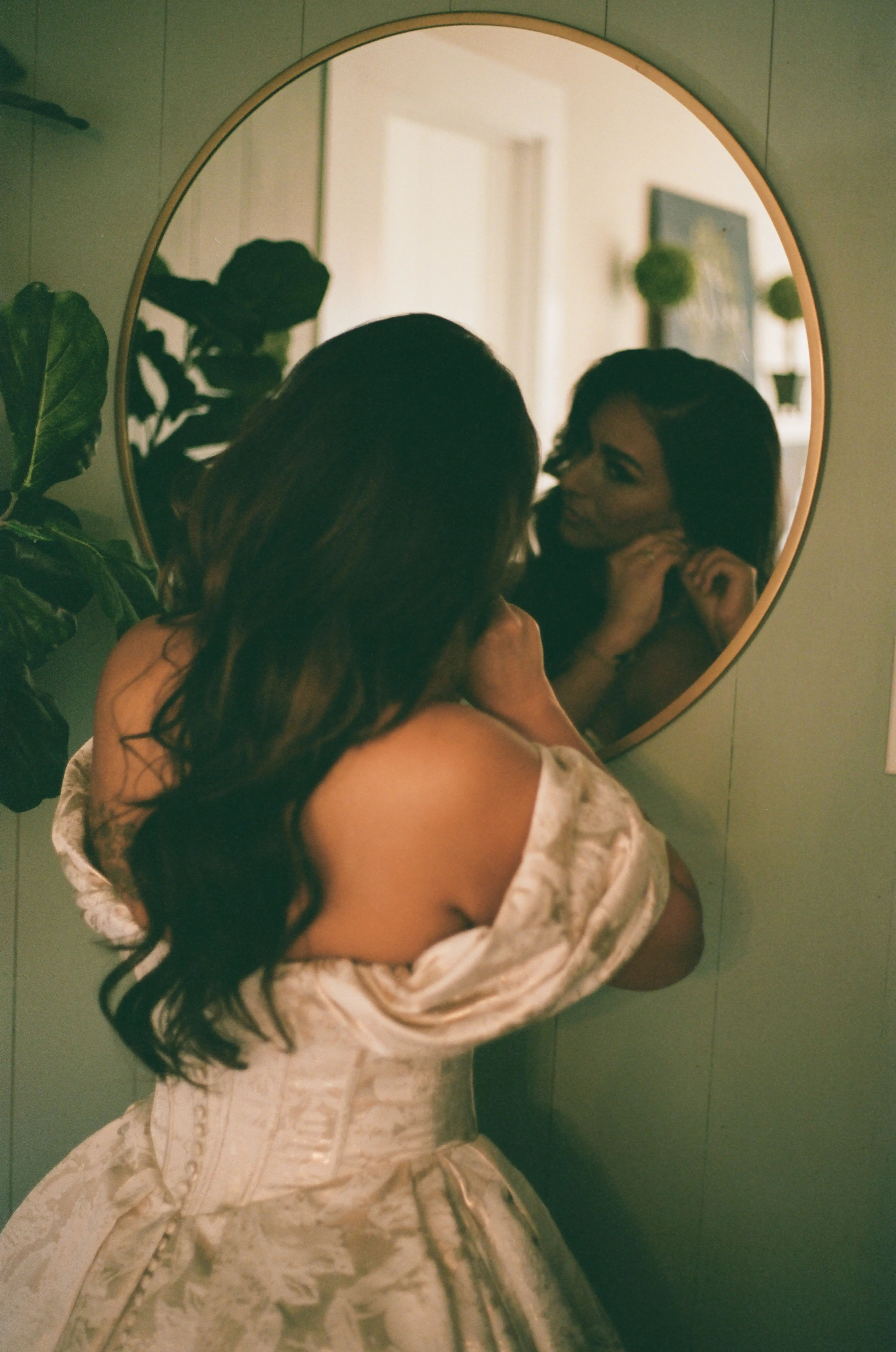 Bride Wearing Floral Ballgown Wedding Dress Called Derrick Marie Putting On Earrings