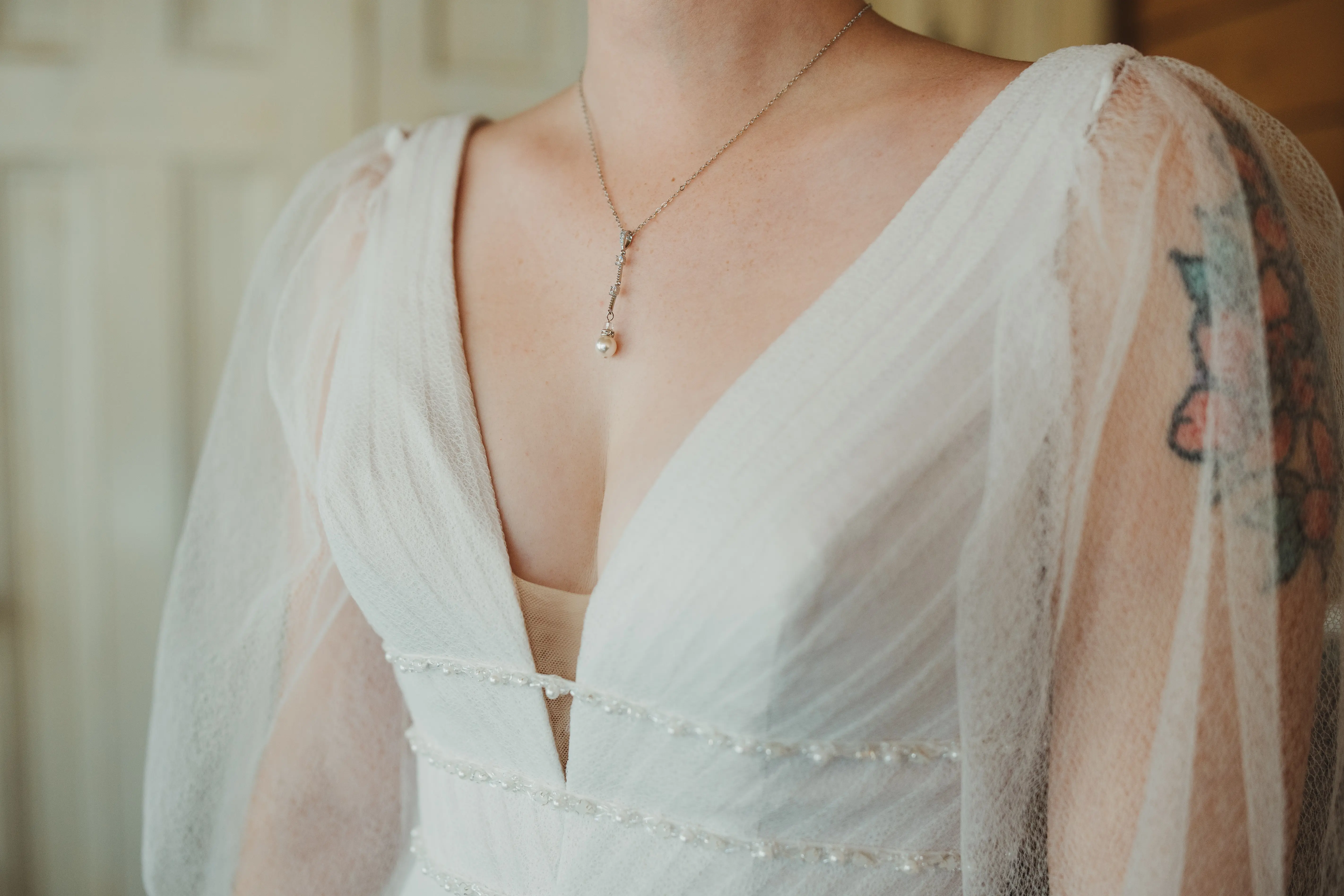 Bride Wearing Long-Sleeve A-Line Wedding Dress Called Joanne By Rebecca Ingram And A Pearl Necklace