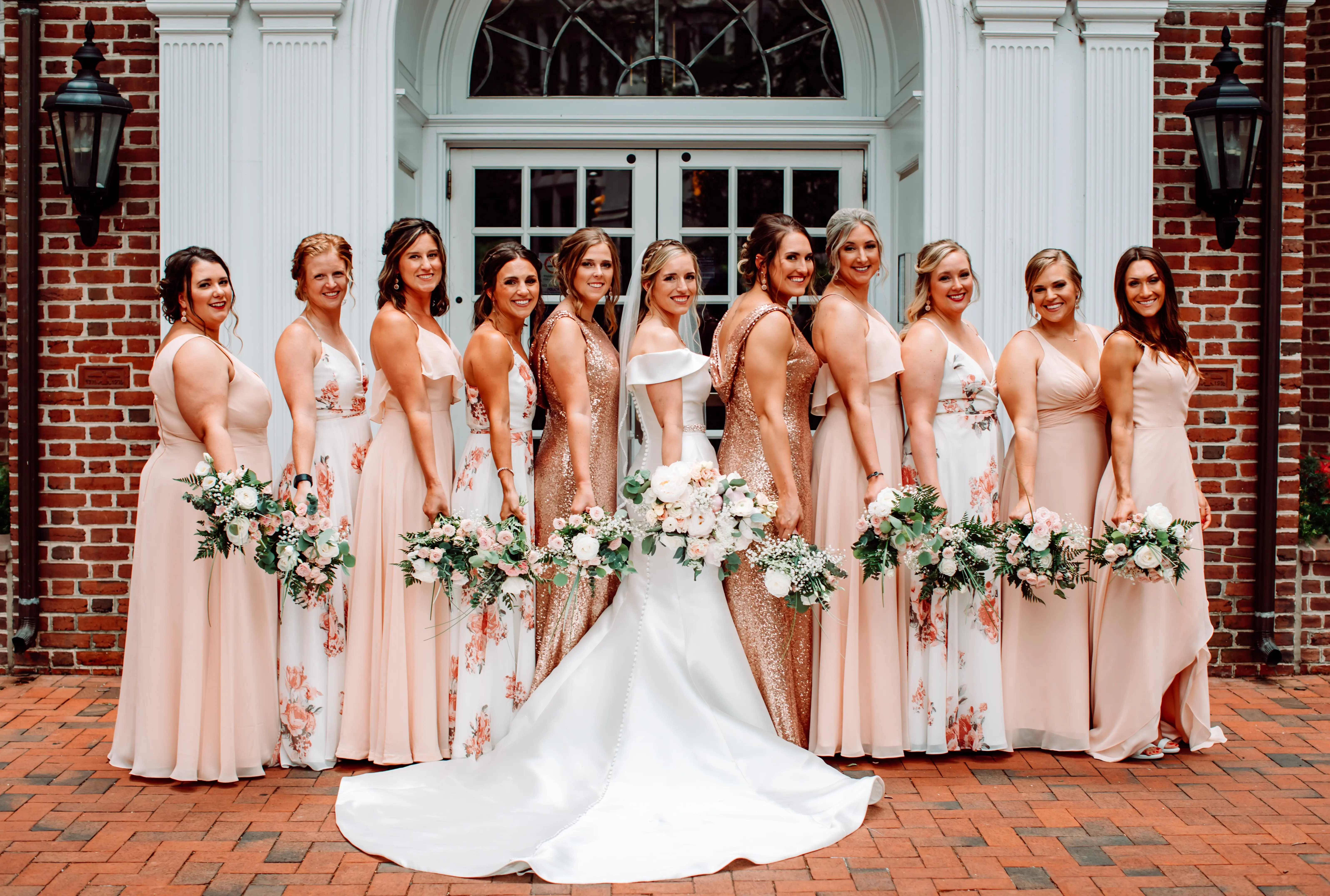 Bride with her bridesmaids wearing mix and match dresses in tones of rose gold, light blush and coral.