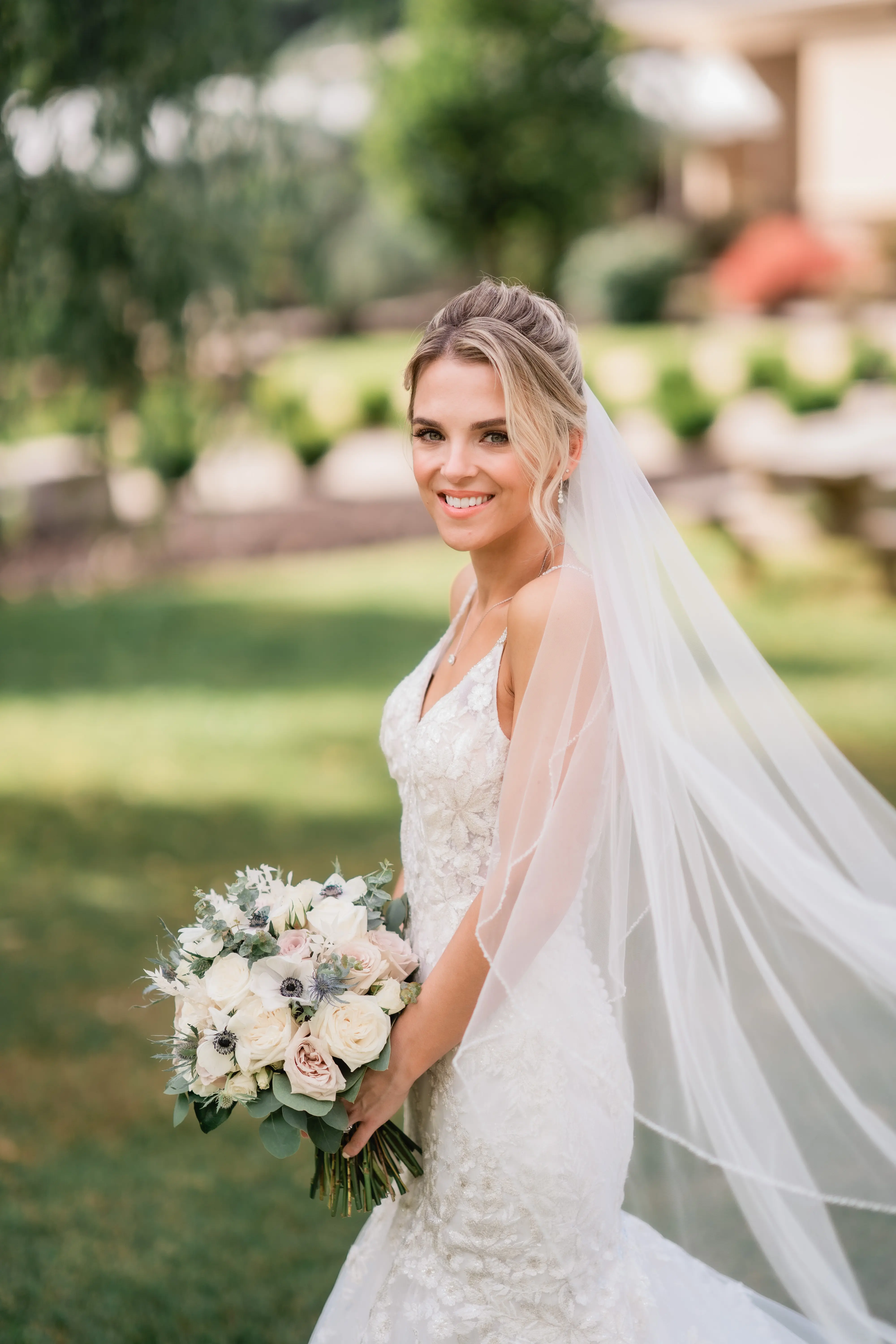 Bride holding pale pink, white and ivory bouquet and flowing veil.