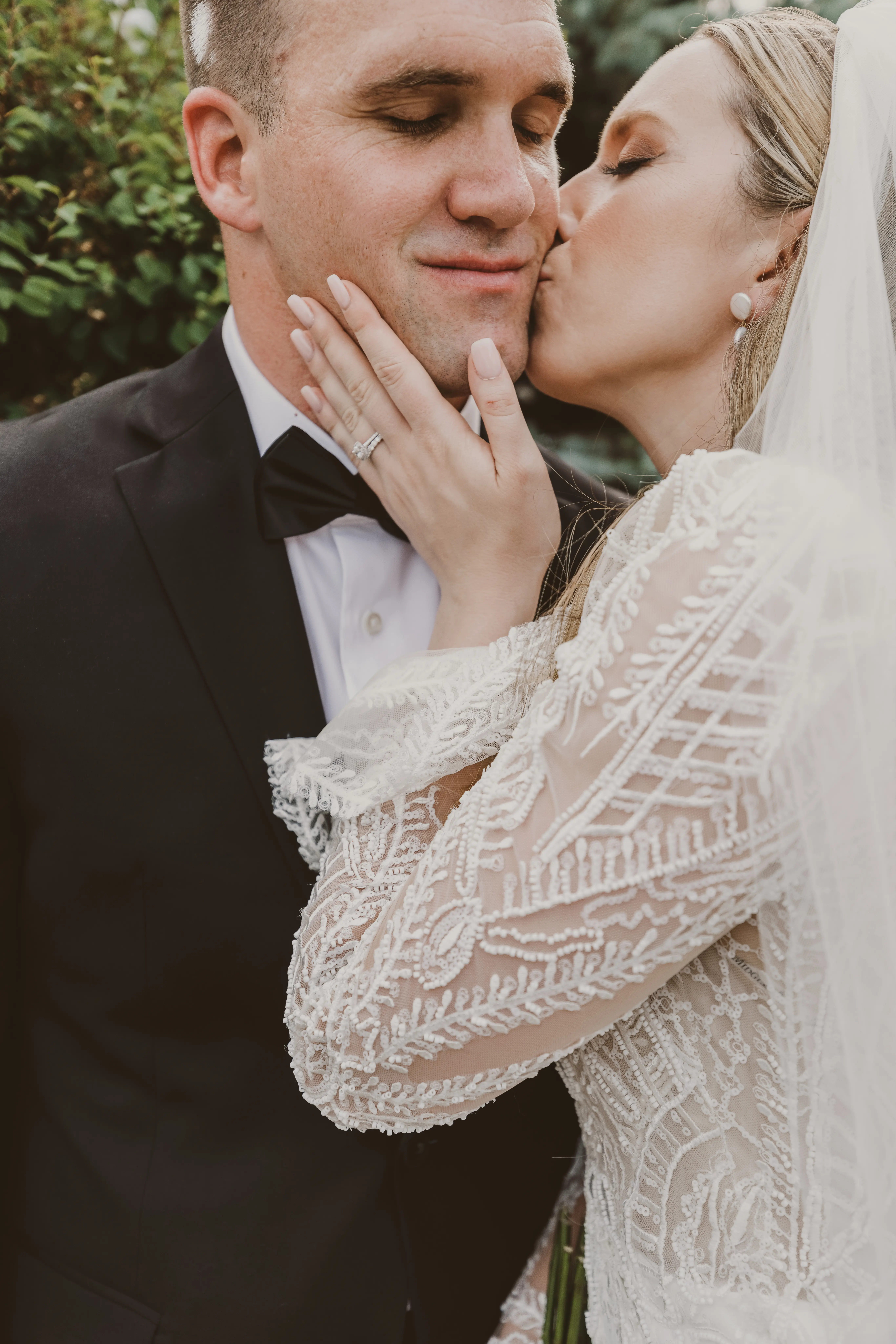 Bride gently kissing groom on the cheek.