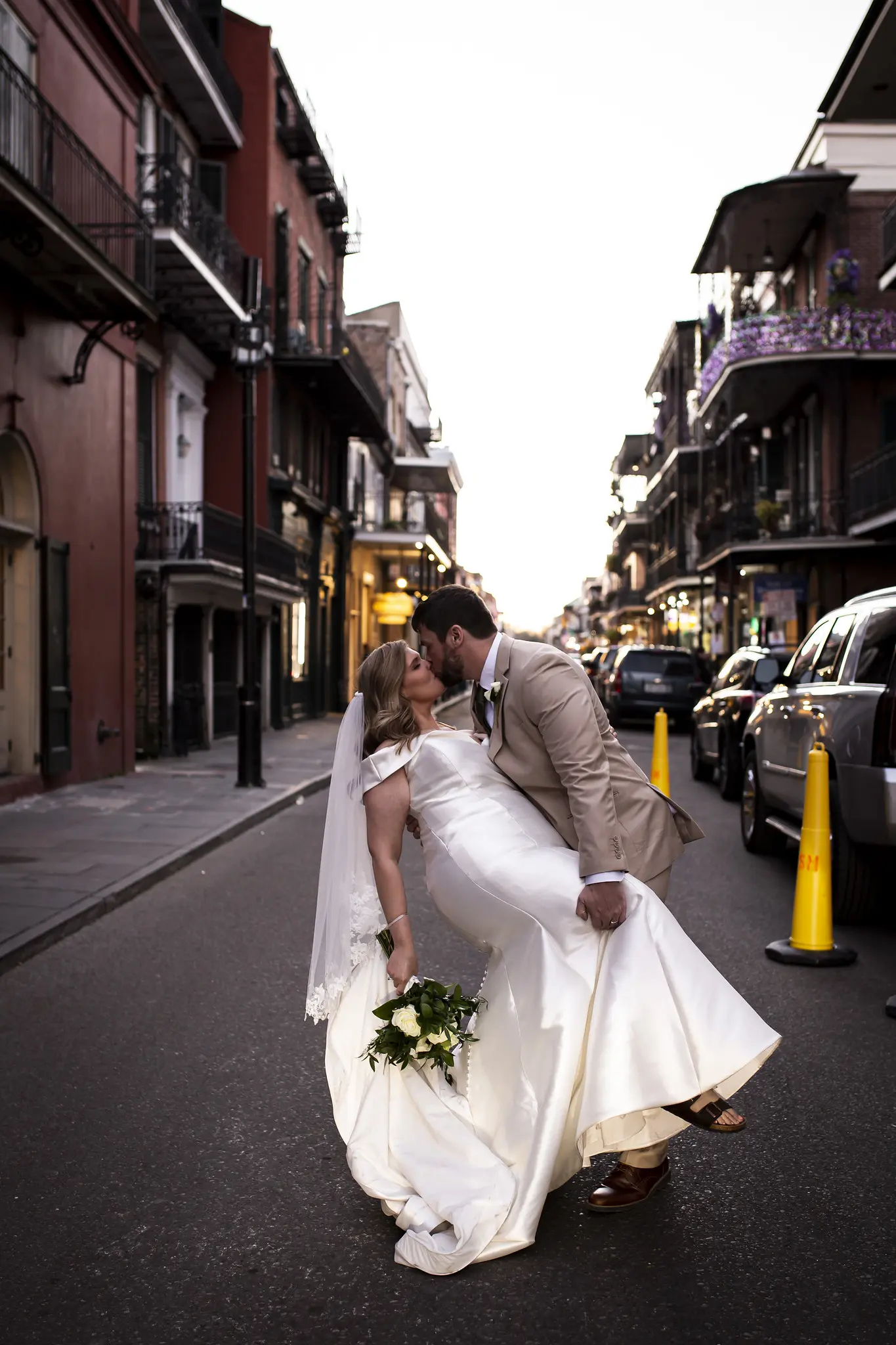 Bride And Groom Share Kiss. Bride Wearing Vintage Glamour Timeless Off-The-Shoulder Fit-And-Flare Wedding Dress Called Josie By Rebecca Ingram