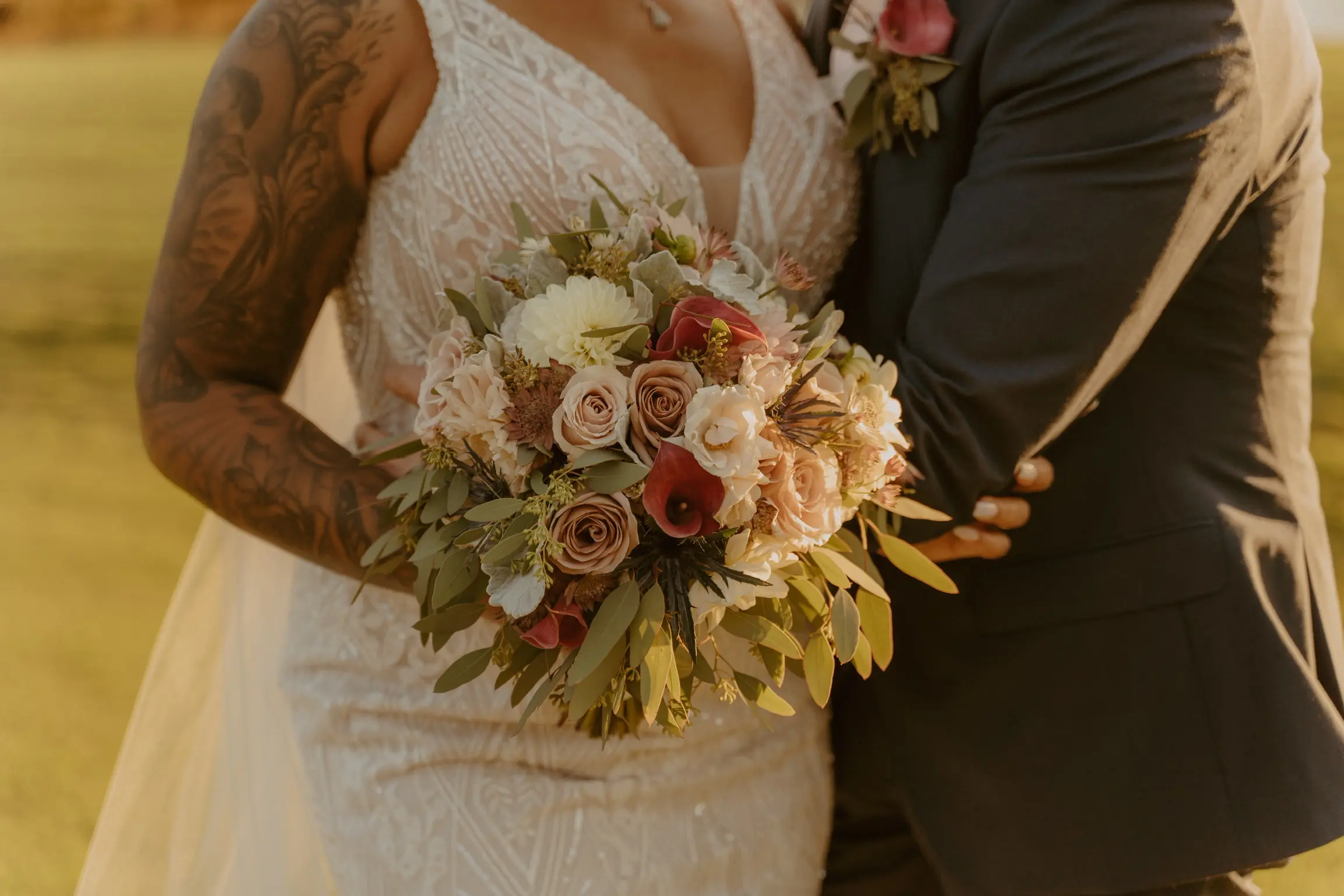 Bride with groom wearing art deco-inspired wedding dress while holding pink and white flower bouquet.