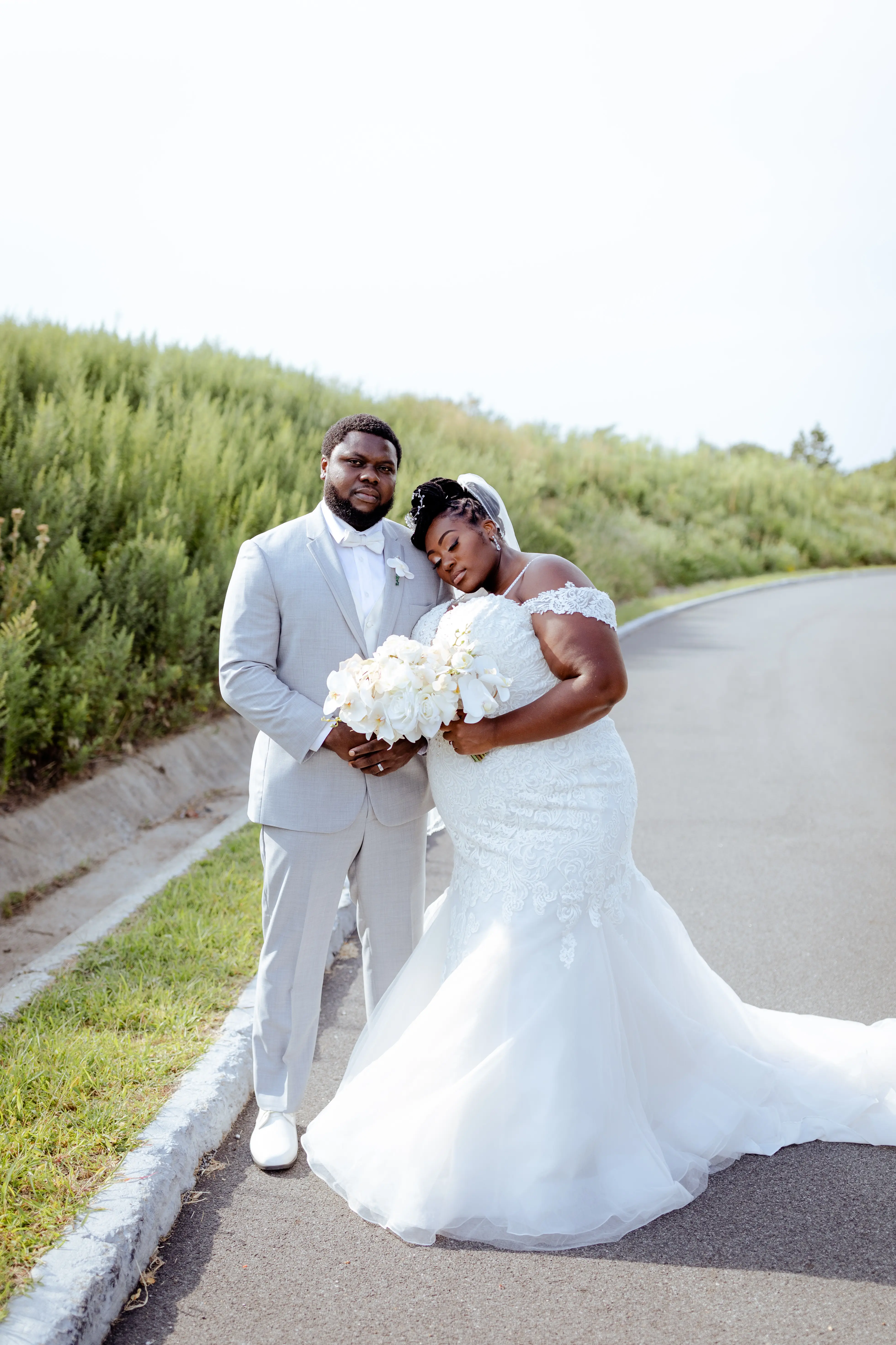 Bride wearing wedding dress called Alistaire Lynette, resting her head on her groom, holding all white bouquet.