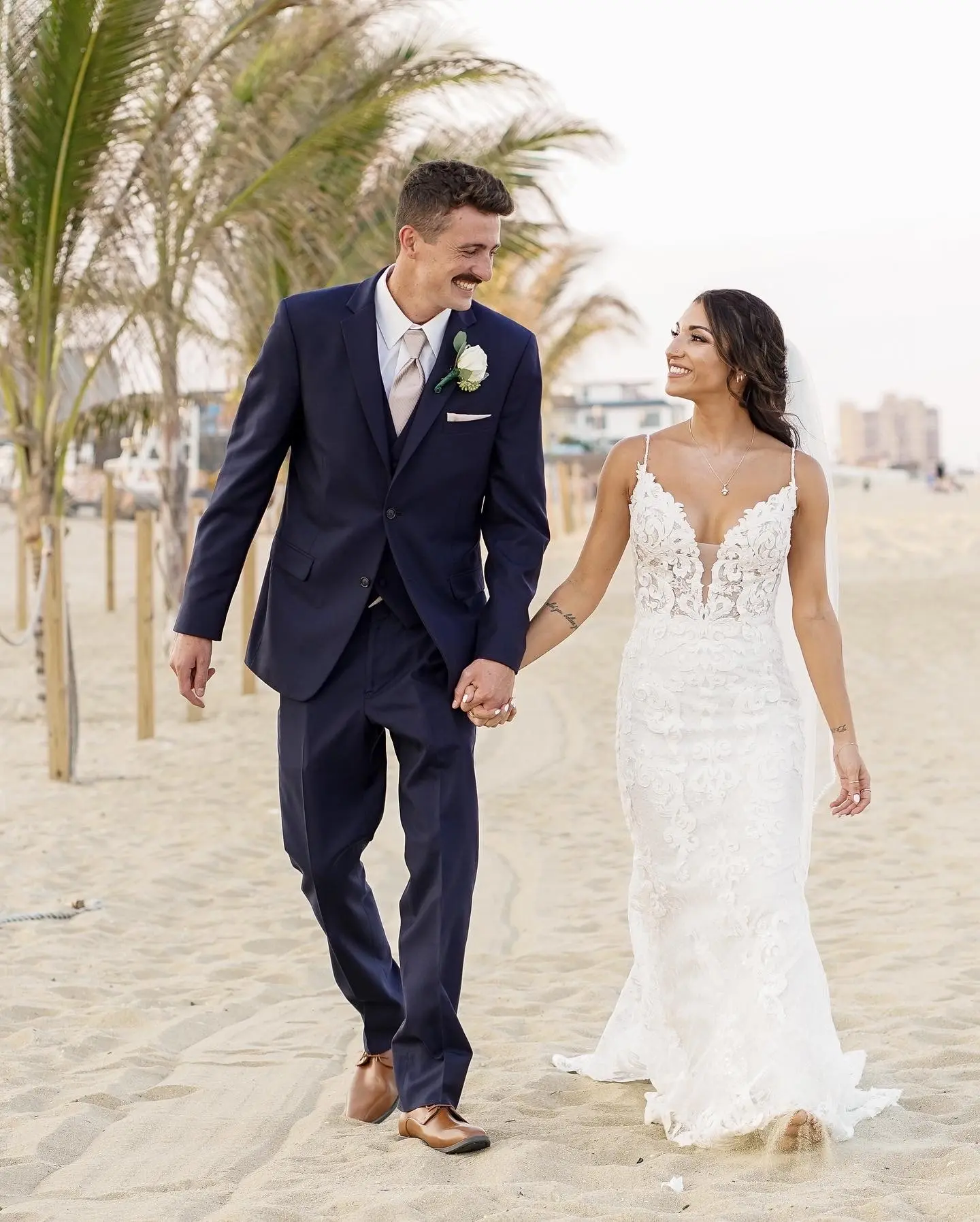 Groom with Bride Walking on Beach Wearing Wedding Dress Called Tuscany by Maggie Sottero.