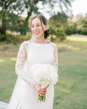 Bride Wearing Simple Long Sleeve Wedding Dress Called Bethany By Rebecca Ingram Holding A White Flower Bouquet