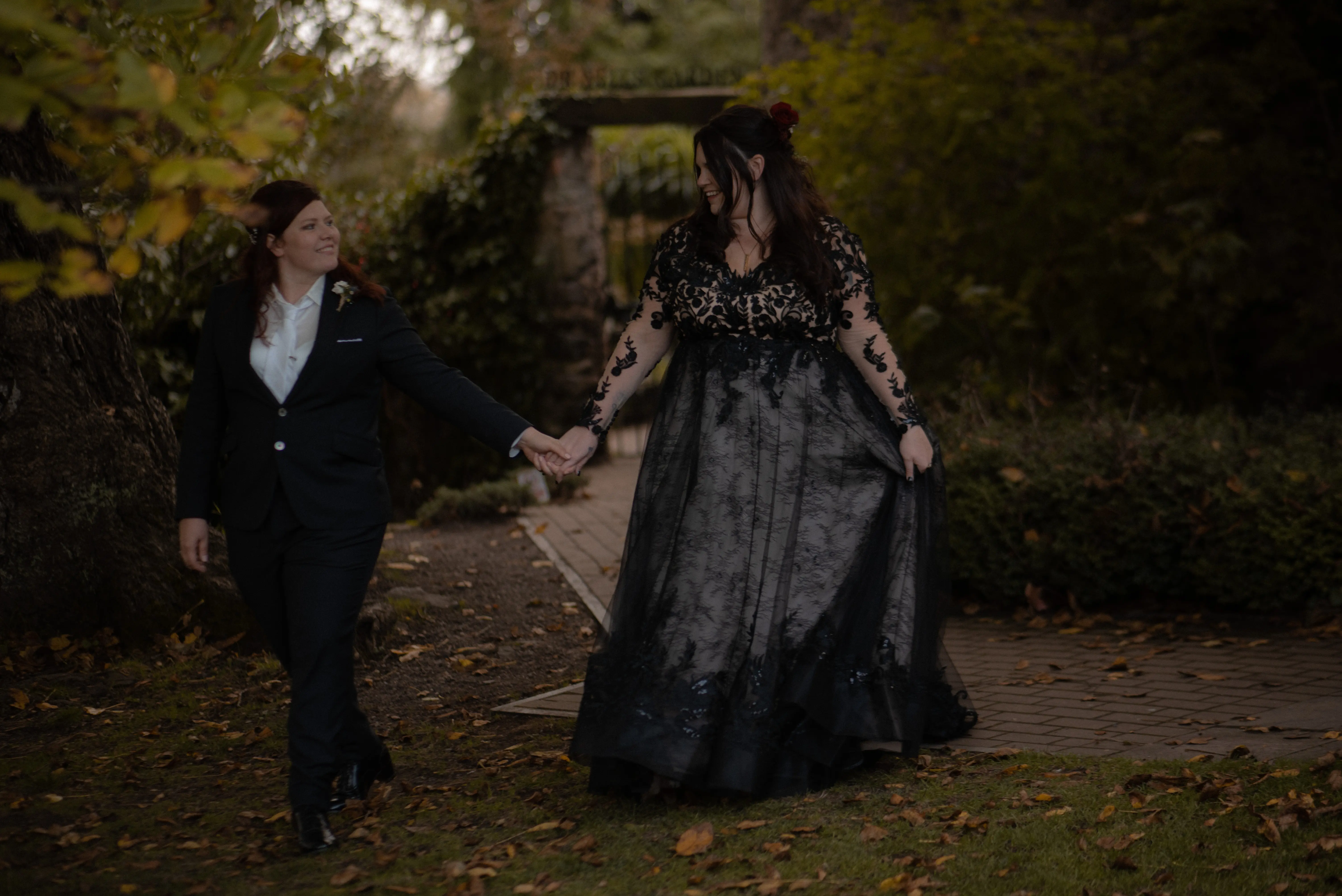 Bride Wearing Black A-Line Wedding Dress Called Zander By Sottero And Midgley Holding Hands With Bride Walking In The Forest