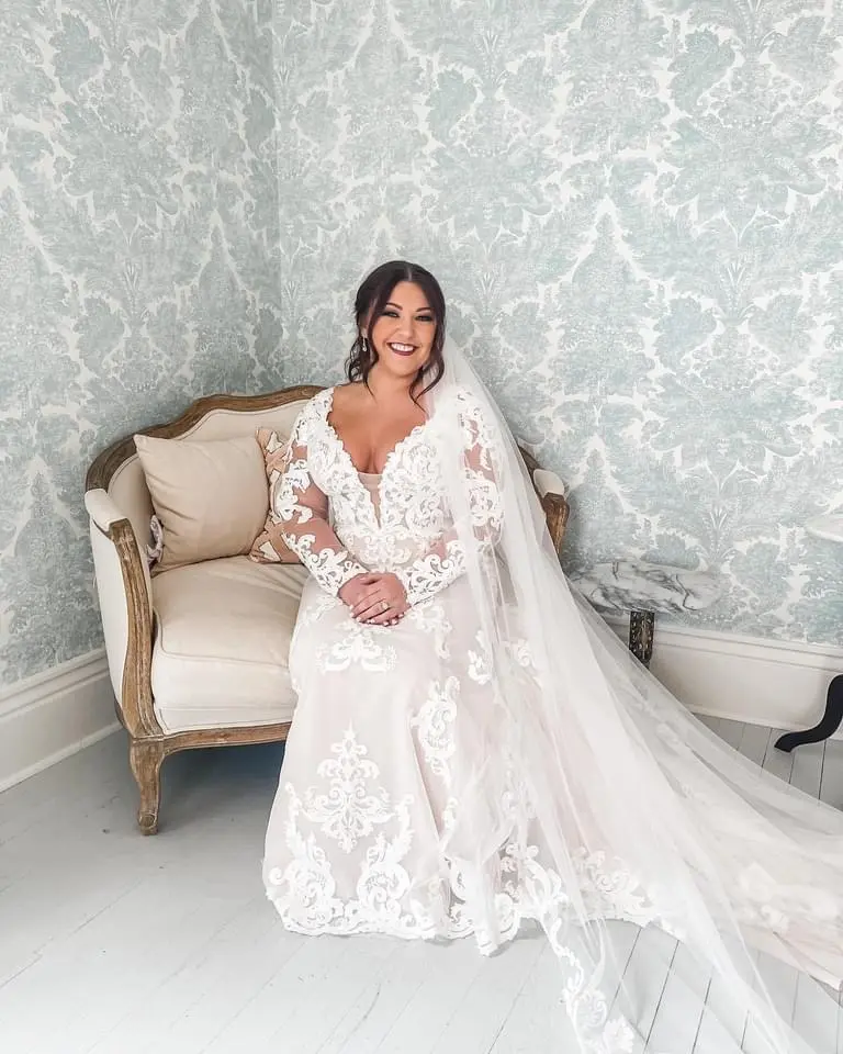 Bride wearing Lace A-line Wedding Dress called Tuscany Lane by Maggie Sottero sitting on a sofa