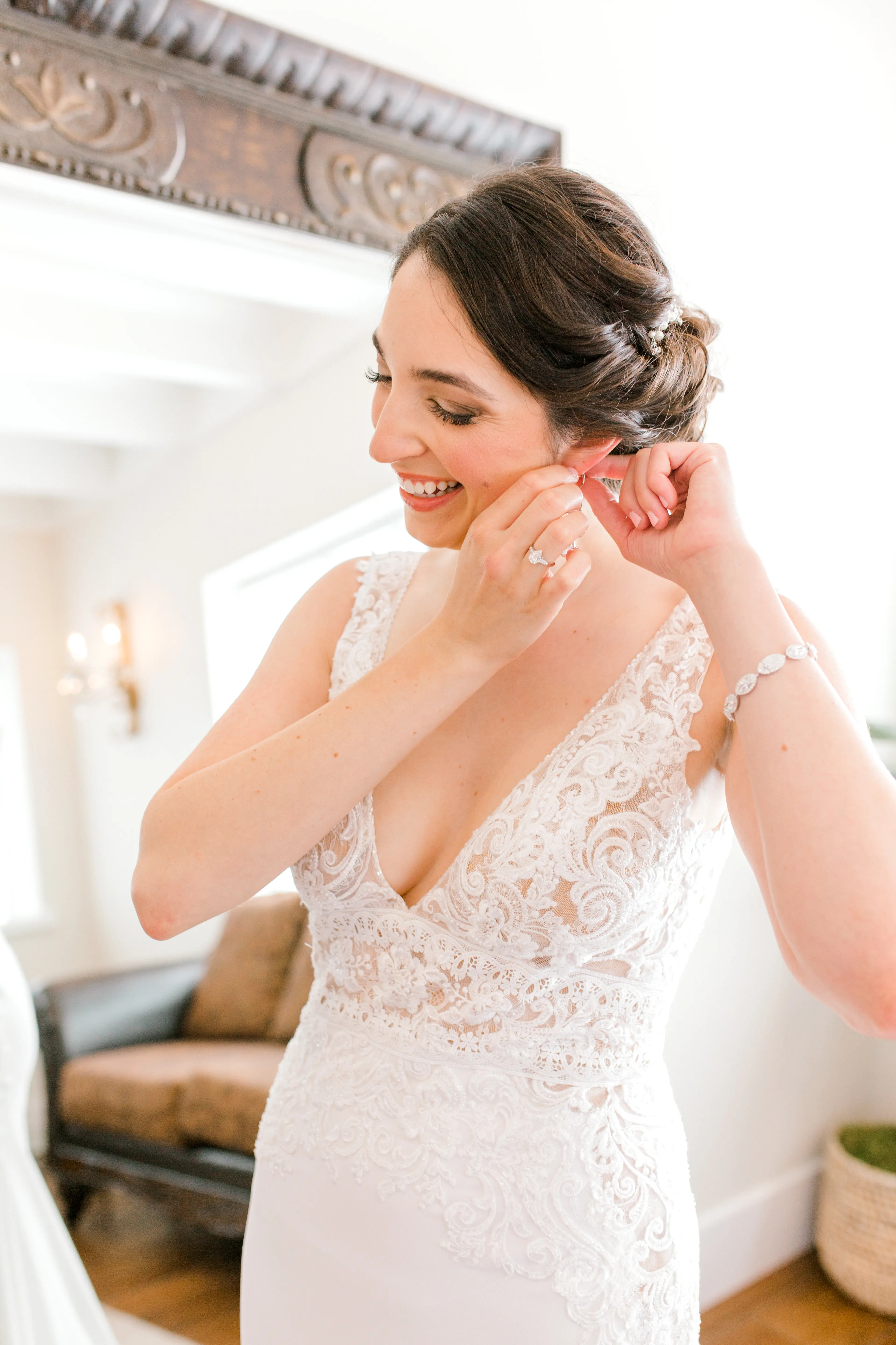 Bride putting her earring in and smiling wearing wedding dress called Aidan.