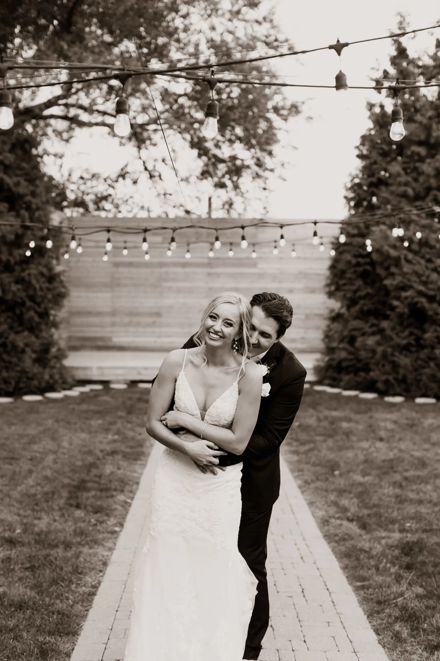 Bride Wearing Sparkle Lace Long Train Wedding Dress Called Fontaine By Maggie Sottero With Groom Hugging From Behind