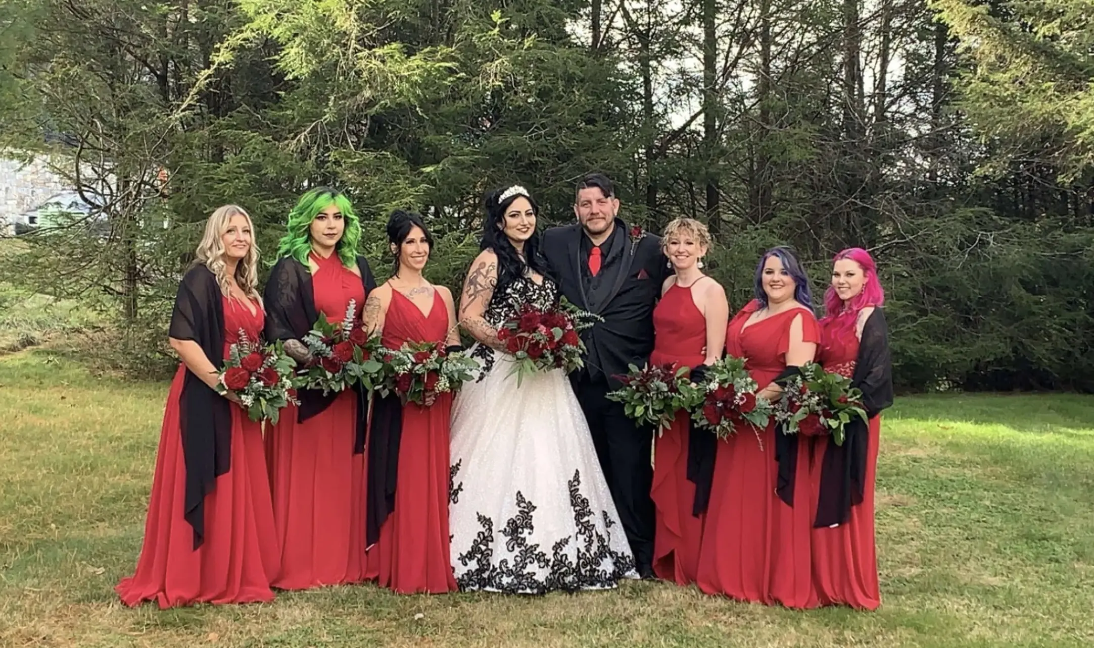 Bride wearing Black Lace Ballgown Wedding Dress called Tristyn by Maggie Sottero, groom, and bridesmaids in red formal gowns