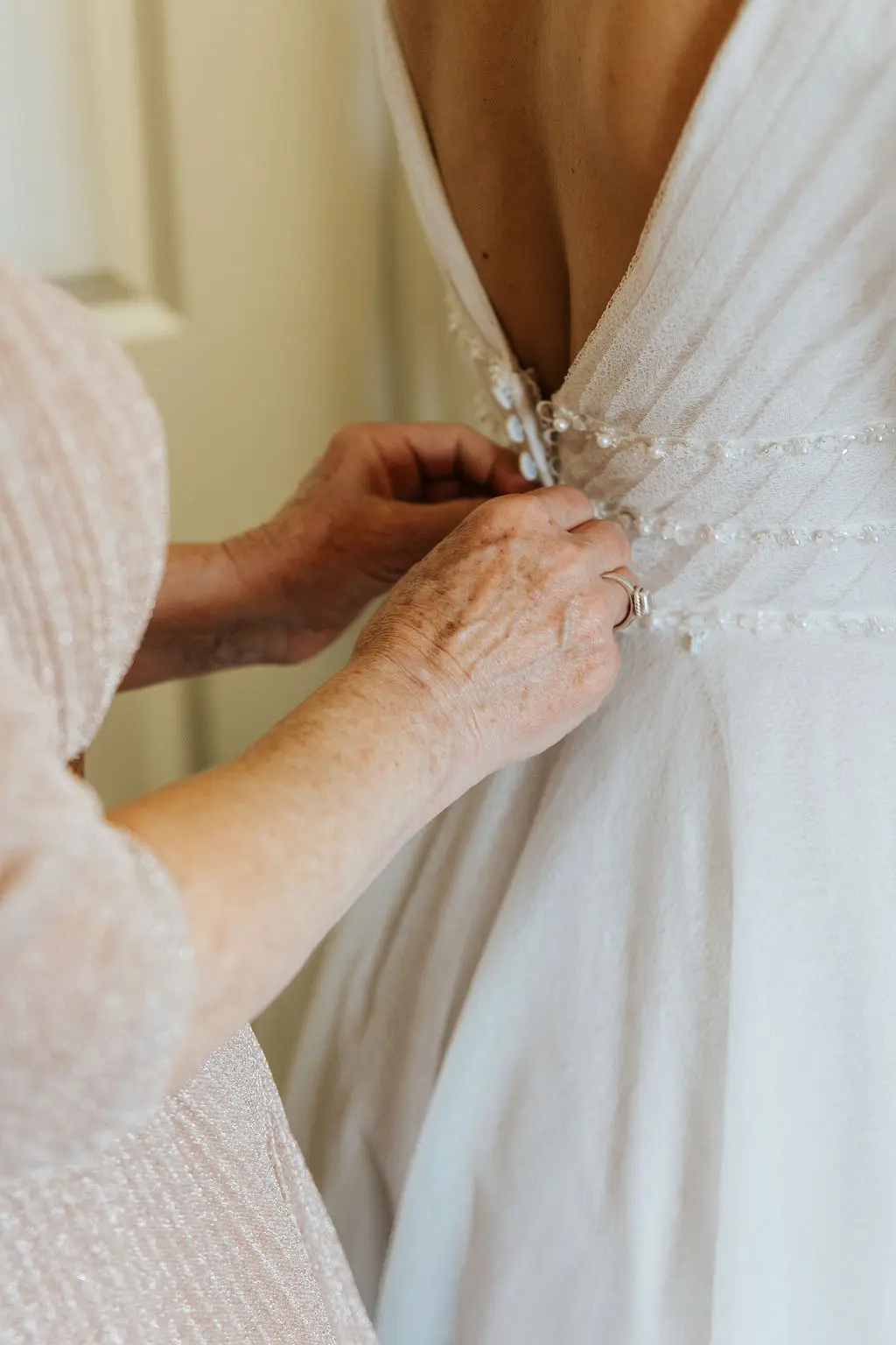 Bride Being Buttoned Up into Sparkly A-Line Wedding Dress.