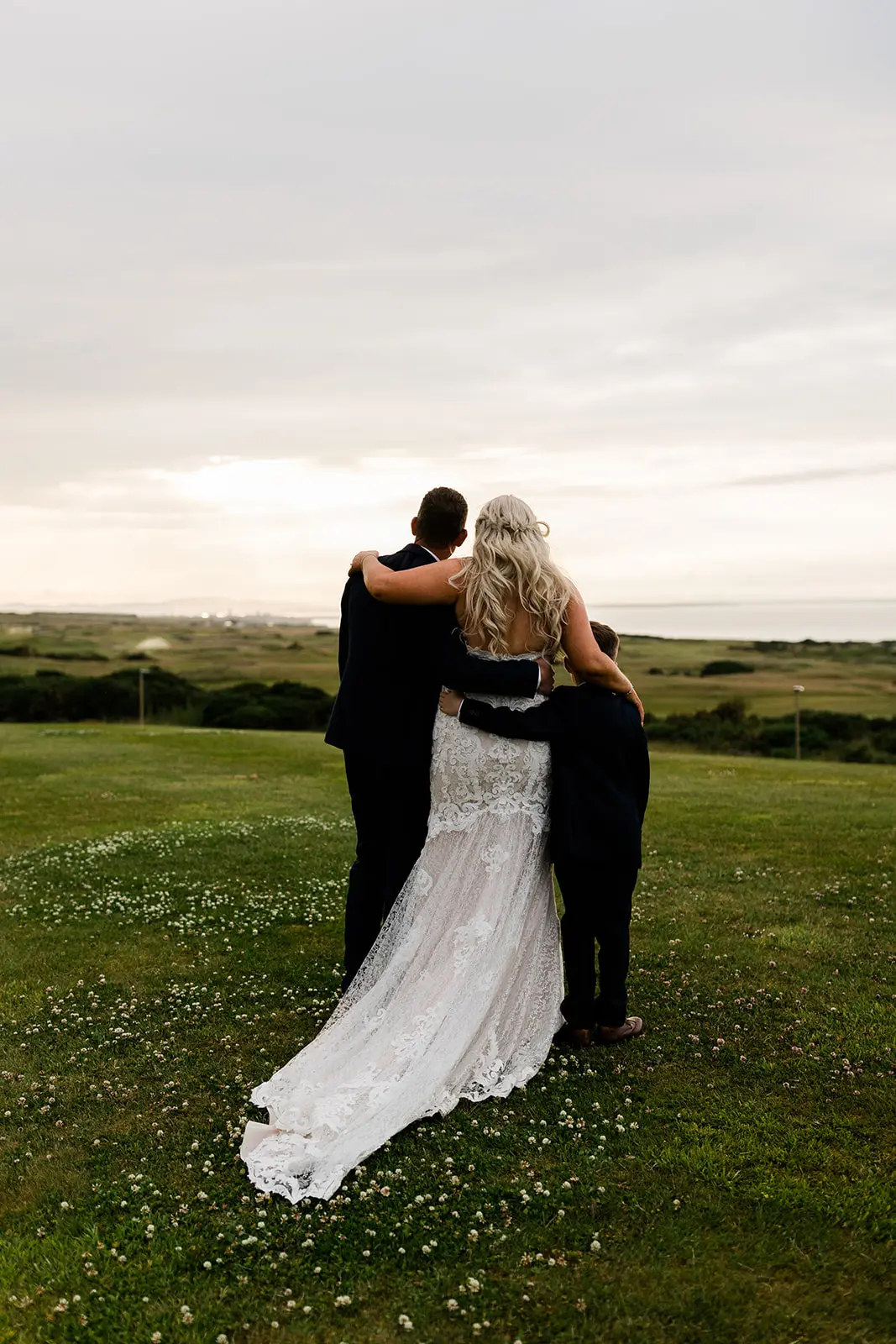Back view of bride, groom and son looking at the sunset.