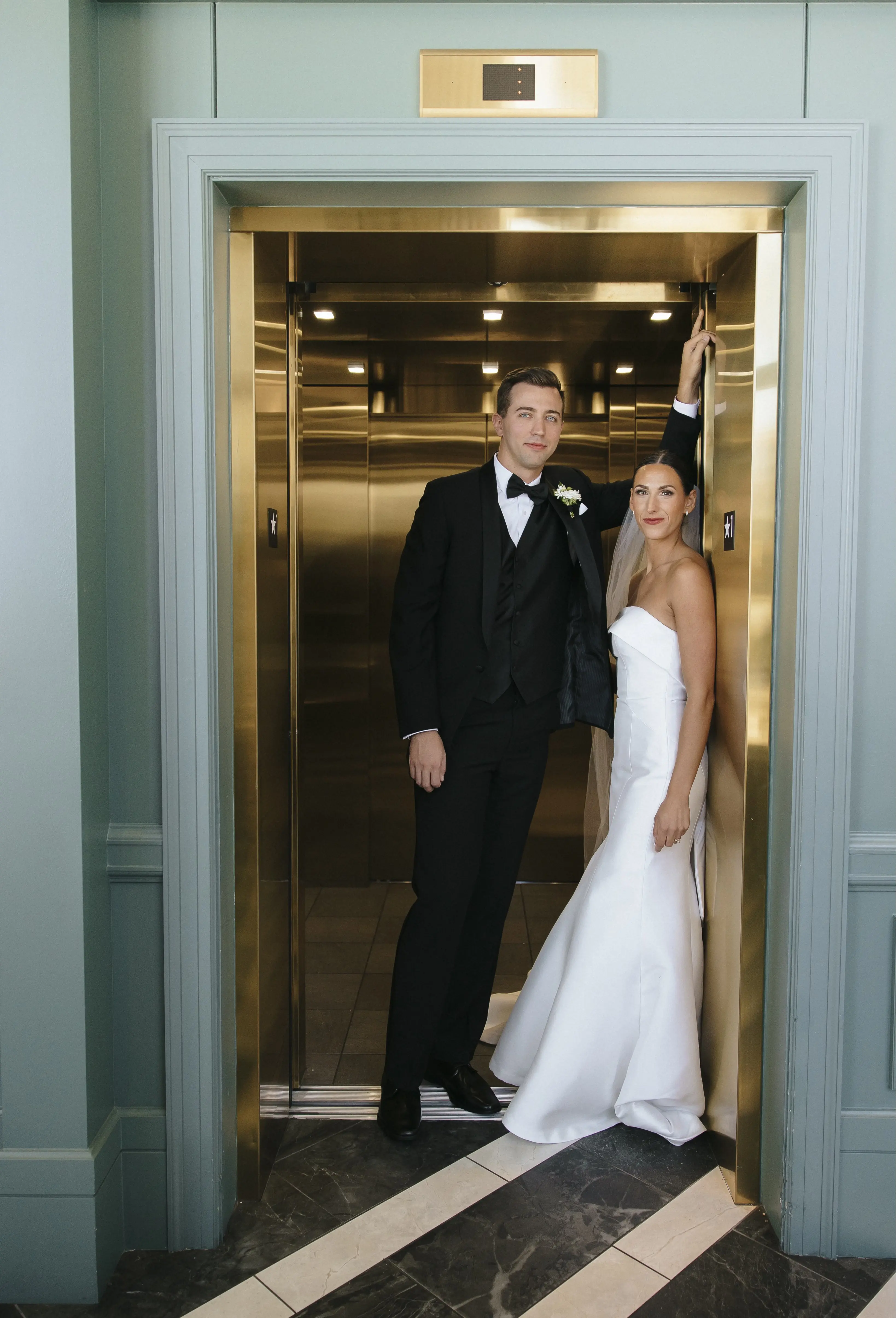 Bride wearing Mitchell wedding dress by Maggie Sottero on an elevator with her husband