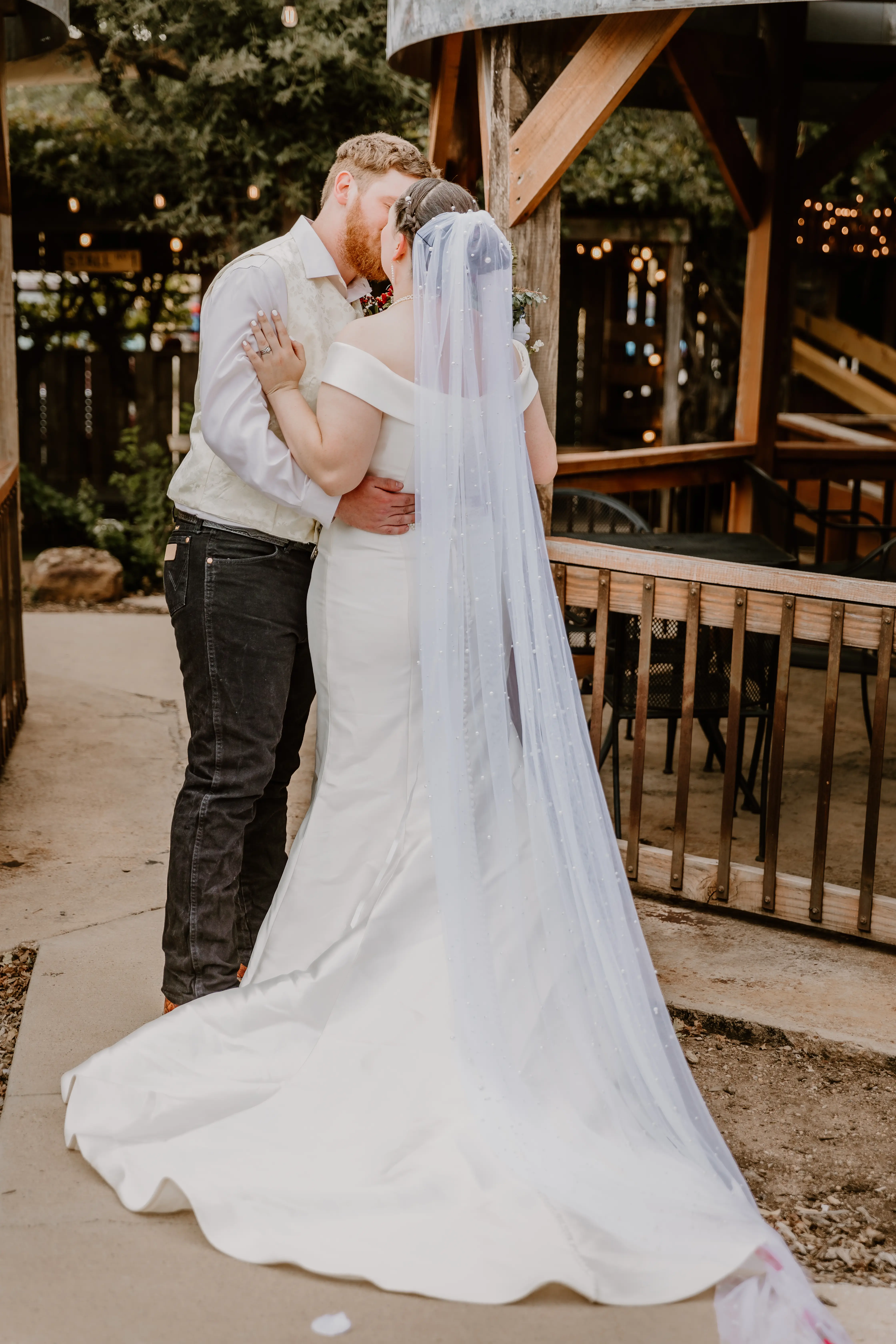 Bride Wearing Simple Fit And Flare Wedding Dress Called Josie By Rebecca Ingram Kissing Groom