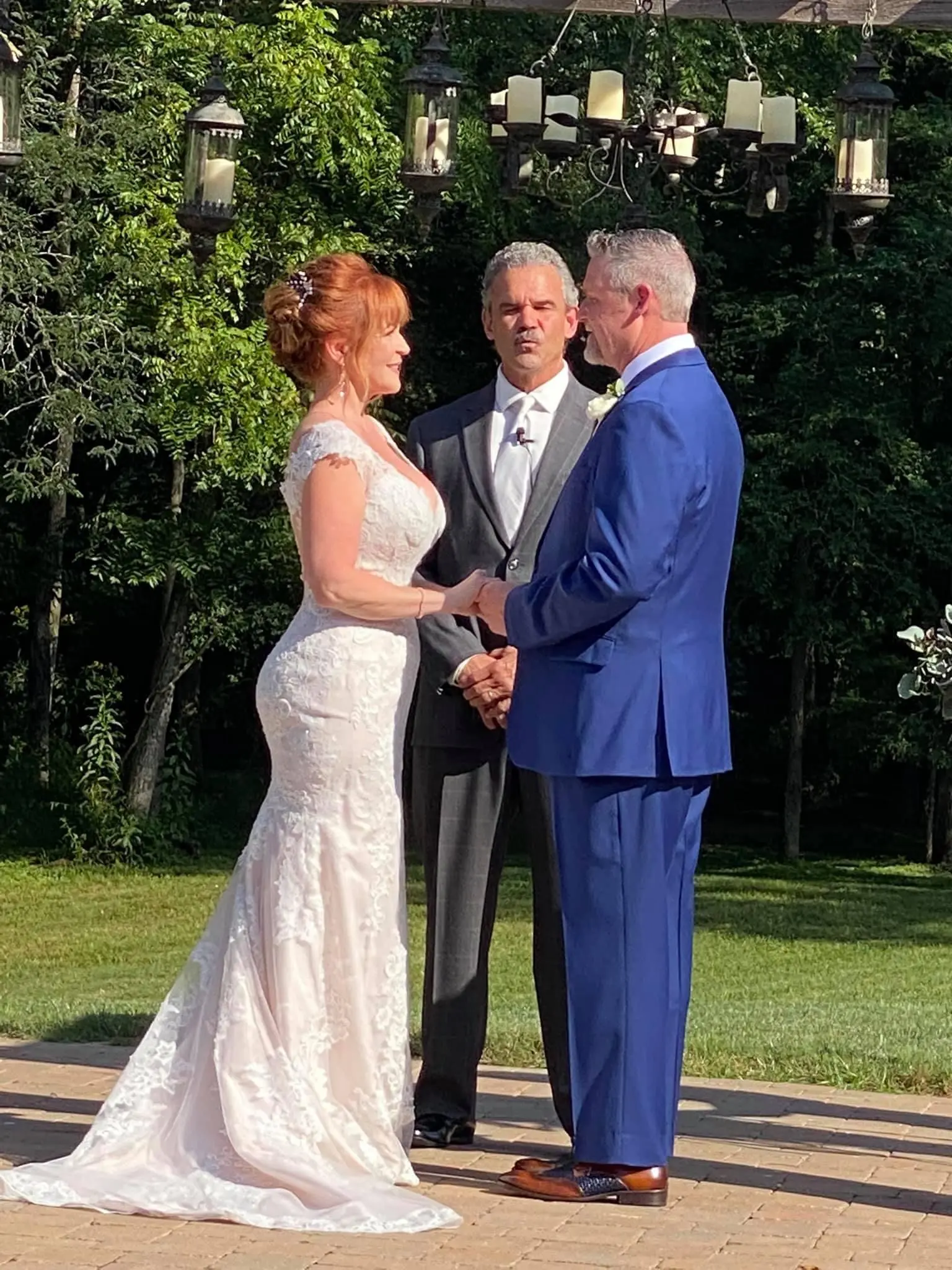 Groom and Bride Exchanging Vows Wearing a Lace Bridal Dress Called Daphne Lynette by Rebecca Ingram