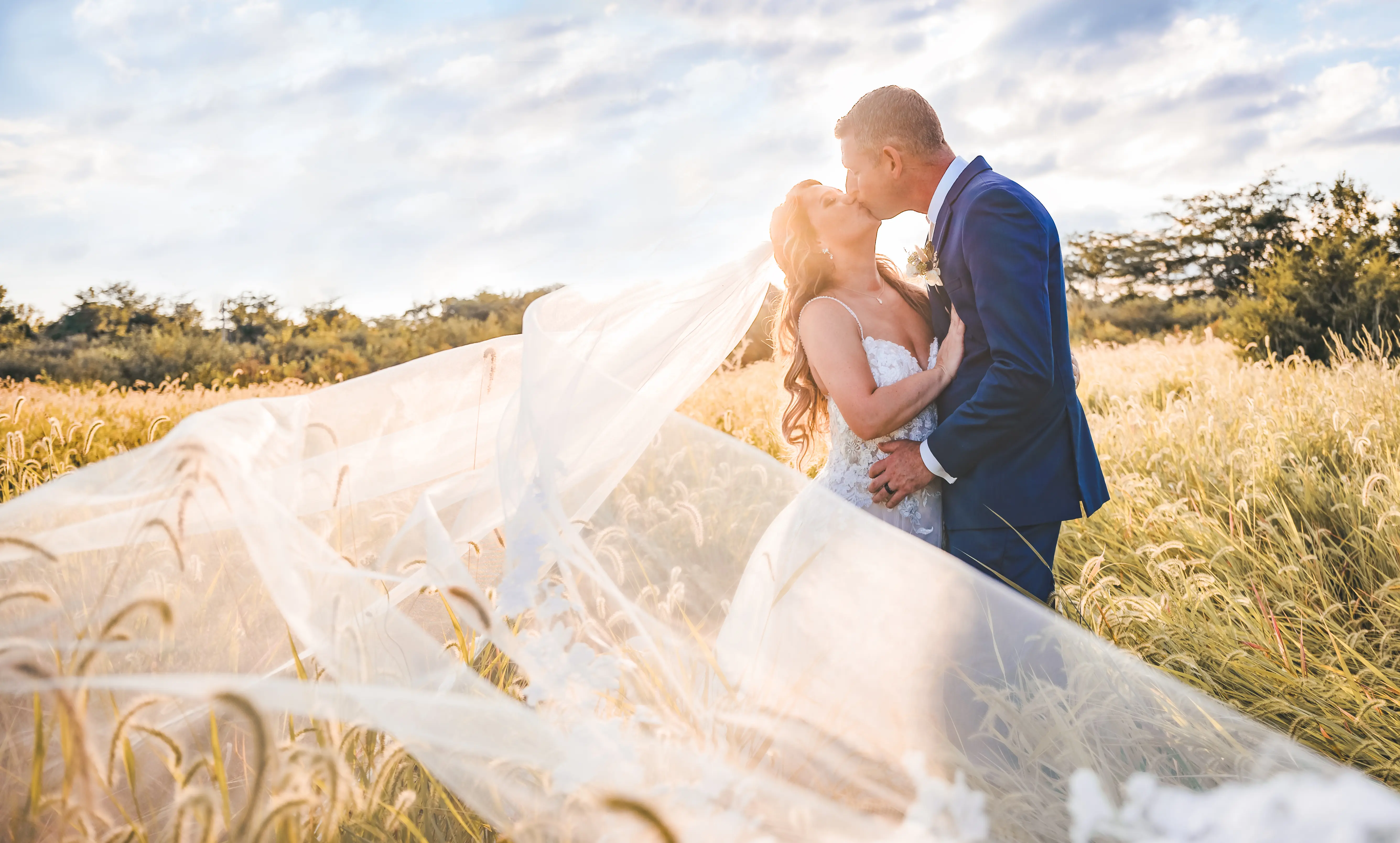 Bride Wearing Lace Princess Wedding Dress Called Stevie By Maggie Sottero Kissing Groom In A Field