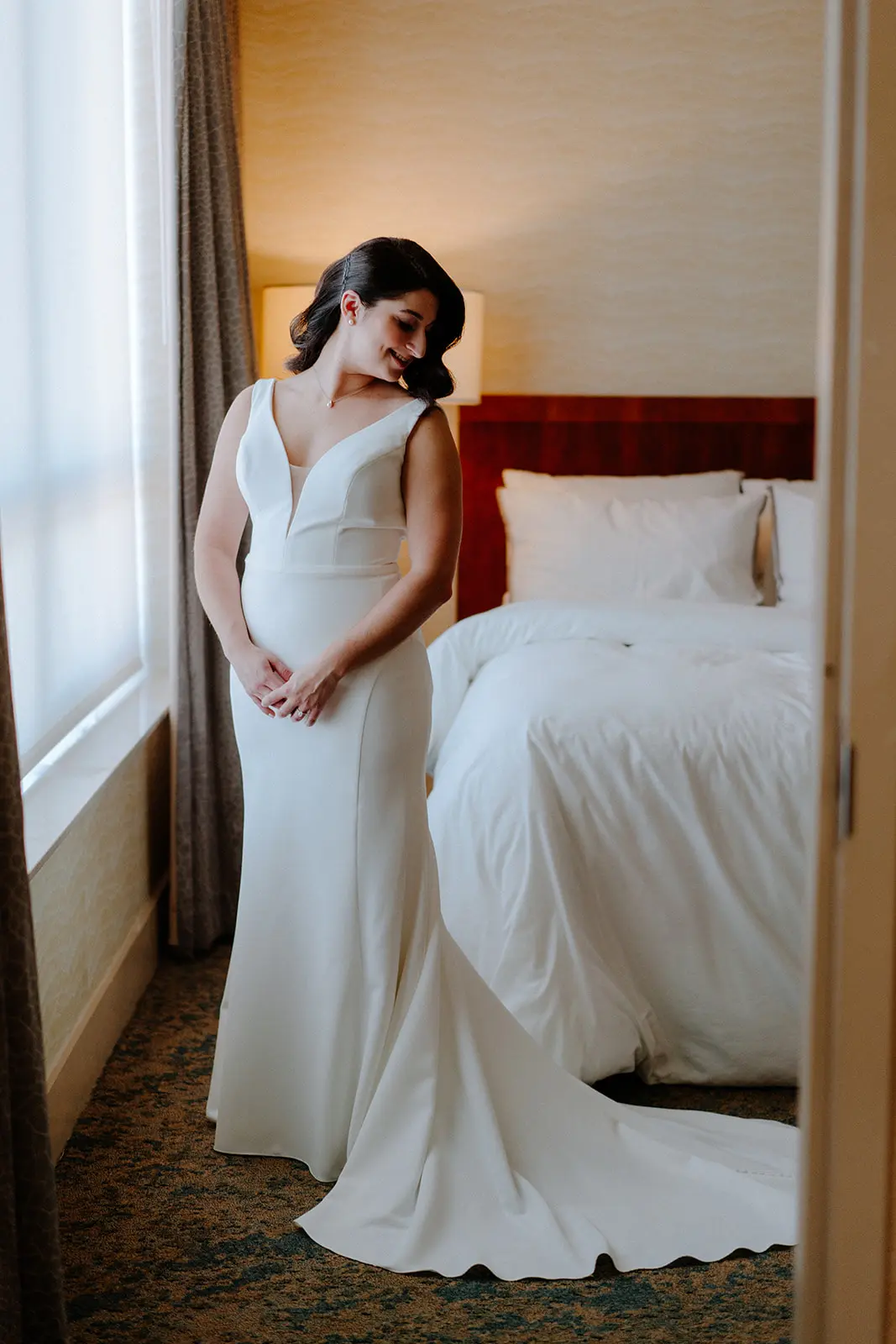 Bride Wearing Simple Wedding Dress Called Theodora By Rebecca Ingram In A Hotel Room