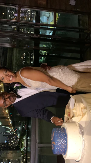Bride And Groom Cutting The Cake With City Skyline Backdrop. Bride Wearing Dazzling Beaded Art Deco Gown Called Elaine By Maggie Sottero