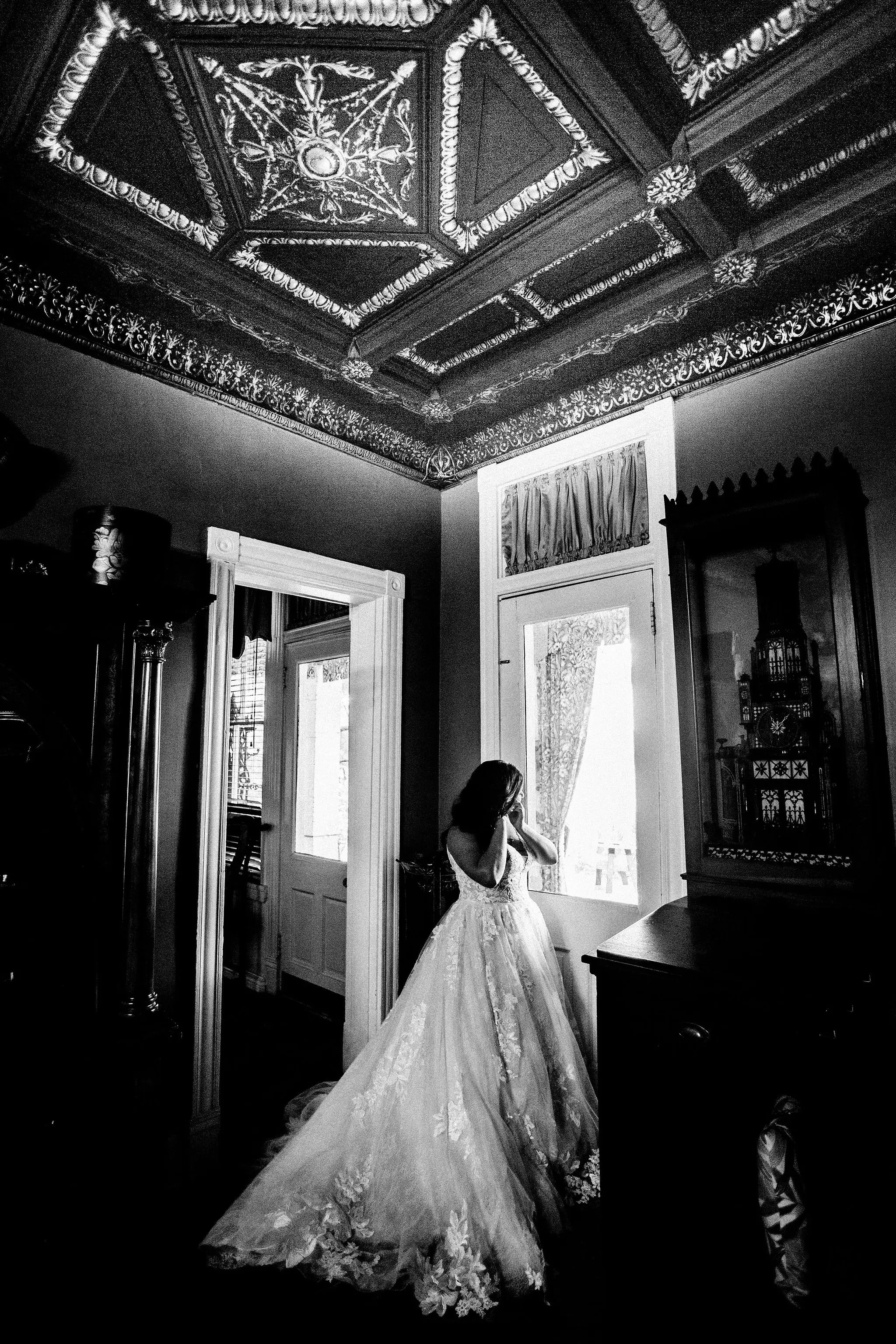 Bride putting in her earrings while looking out the window.