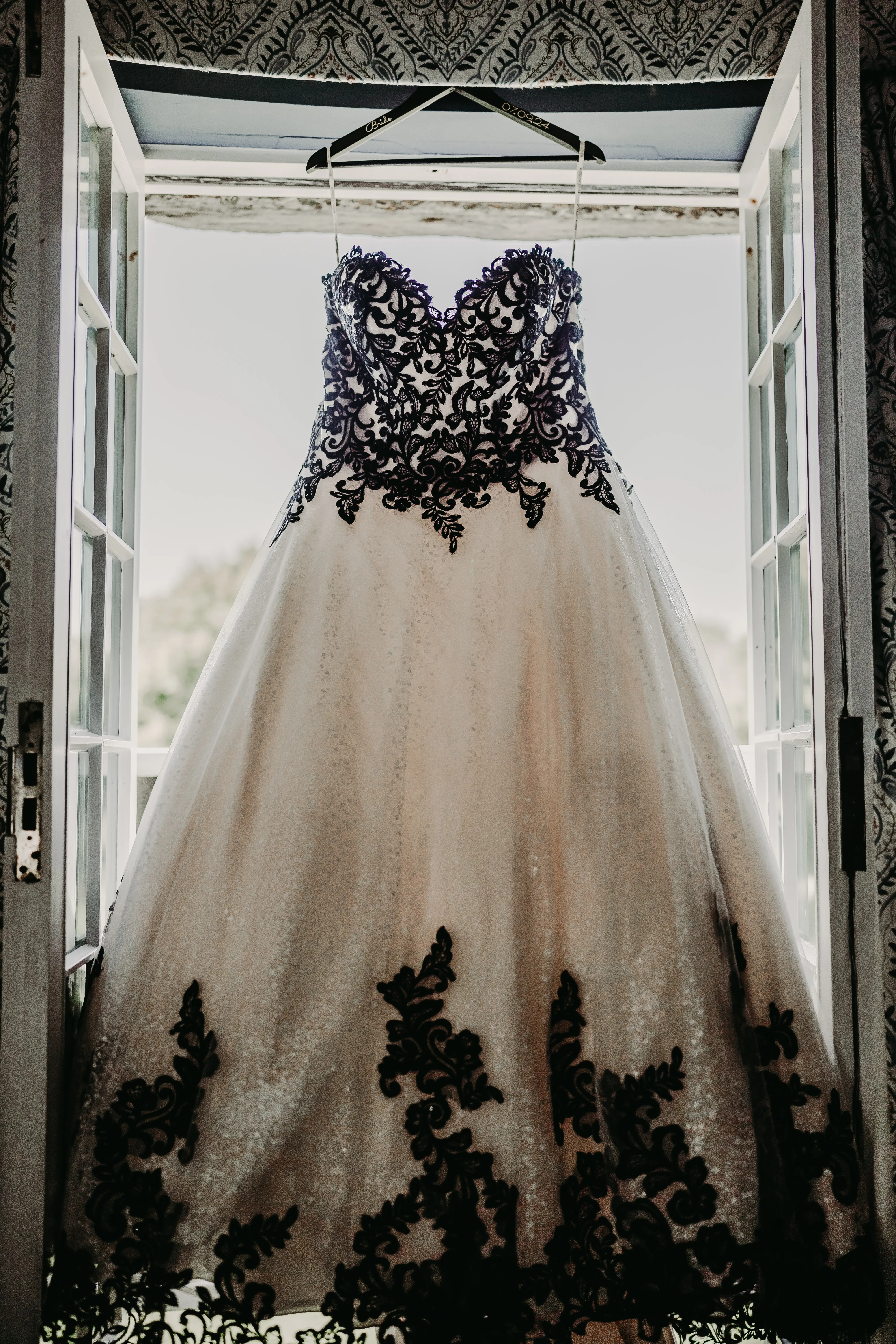 Gothic Black Lace Wedding Dress Called Tristyn By Maggie Sottero Hanging From A Window