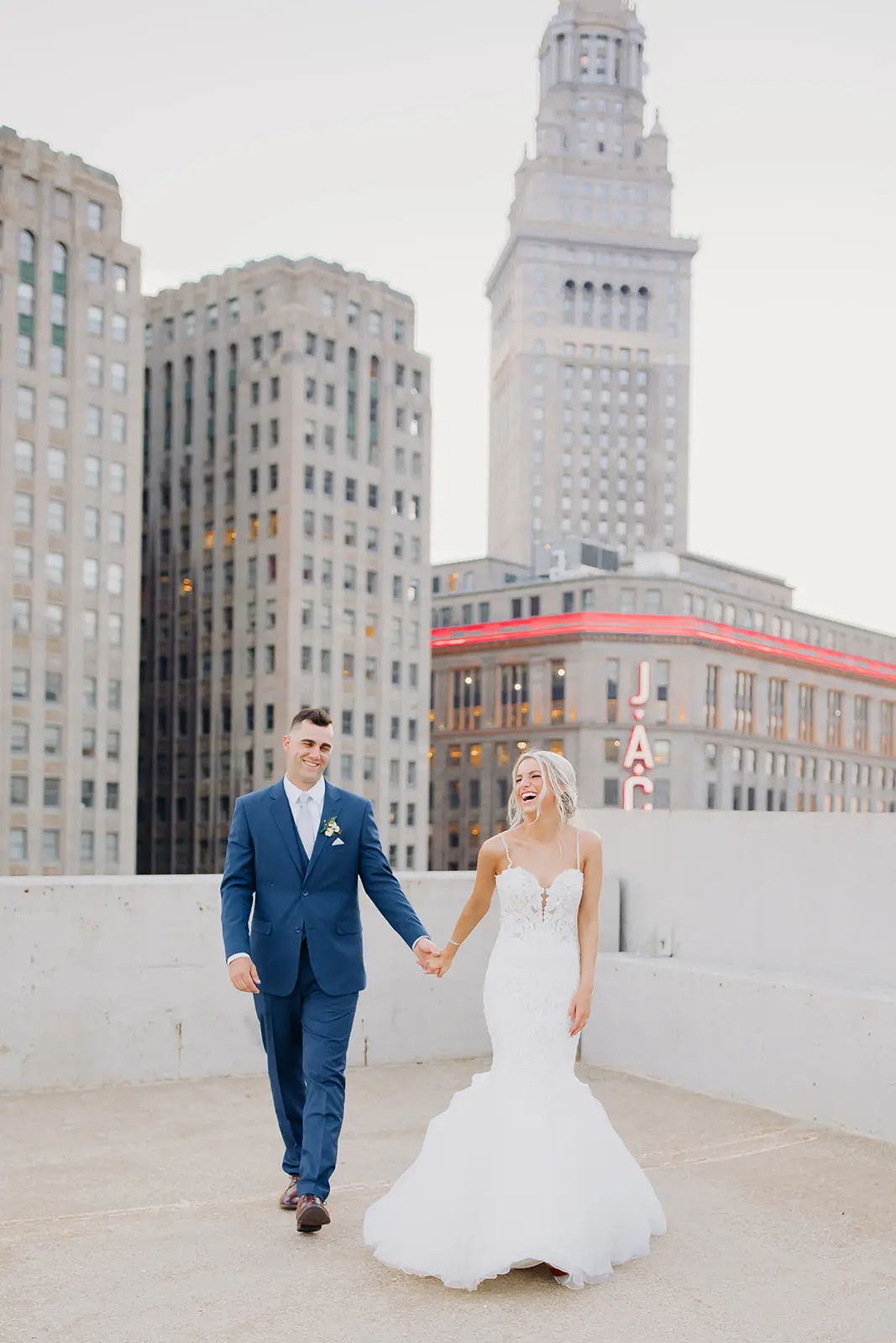 Bride and groom on a rooftop in the city laughing together.
