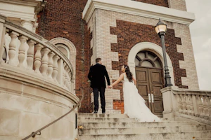 Bride Wearing Floral Lace Wedding Gown Called Laramie By Sottero And Midgley Walking Up Steps With Groom