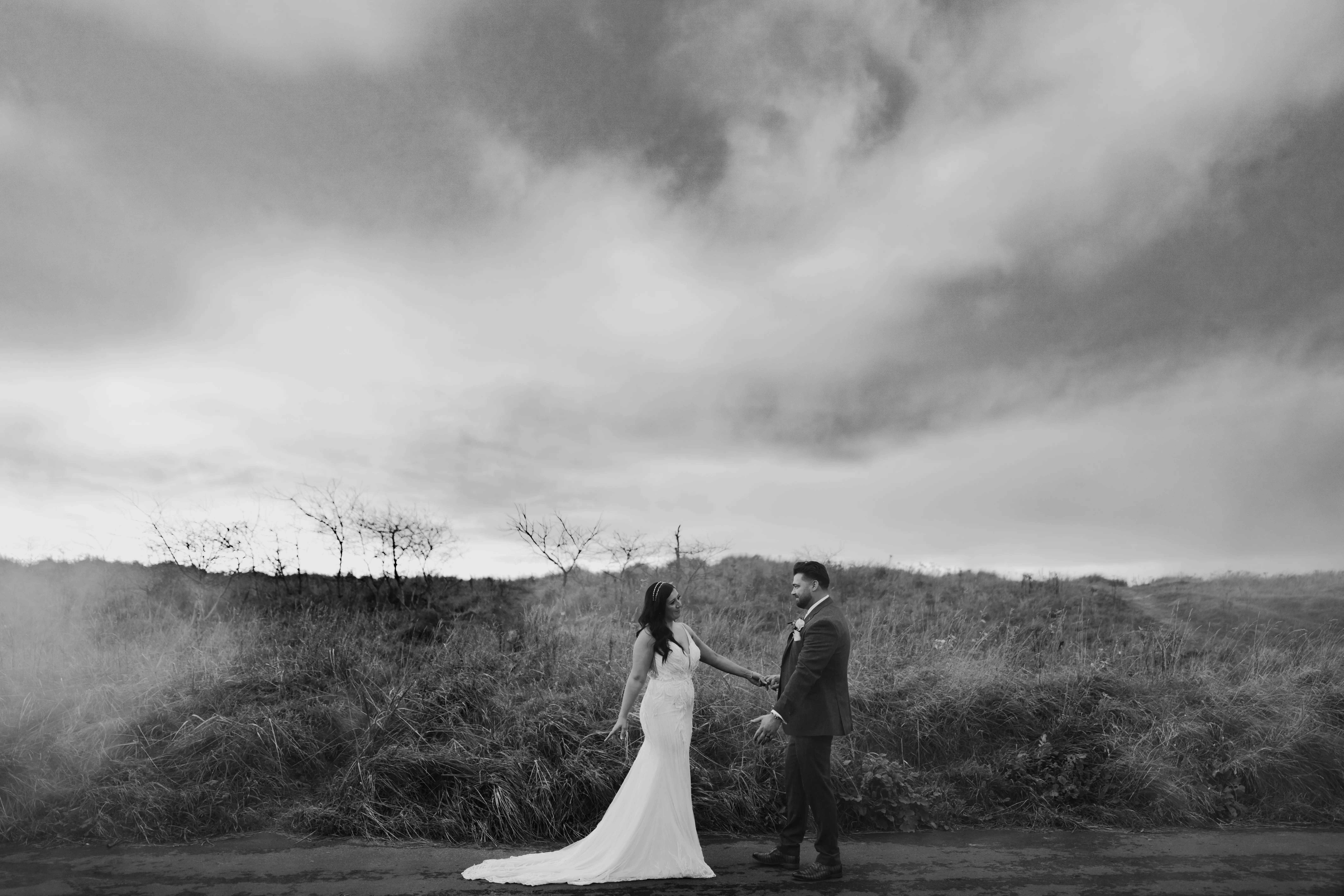 HoBride Wearing Art Deco Wedding Dress Called Luella By Sottero And Midgley Holding Hands With Groom In A Field
