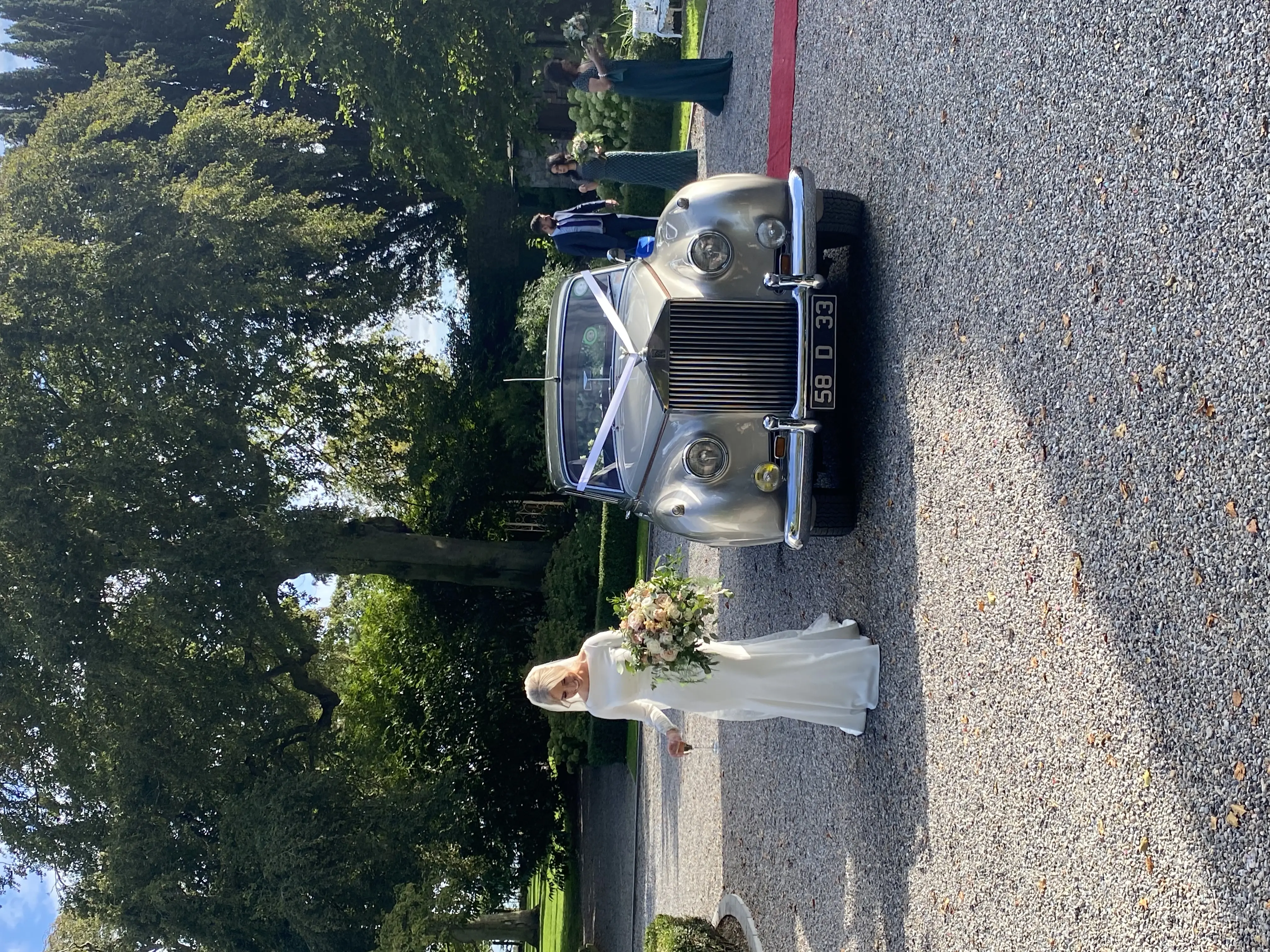 Bride Wearing Simple Crepe Wedding Dress Called Aston By Sottero And Midgley Next To A Vintage Car
