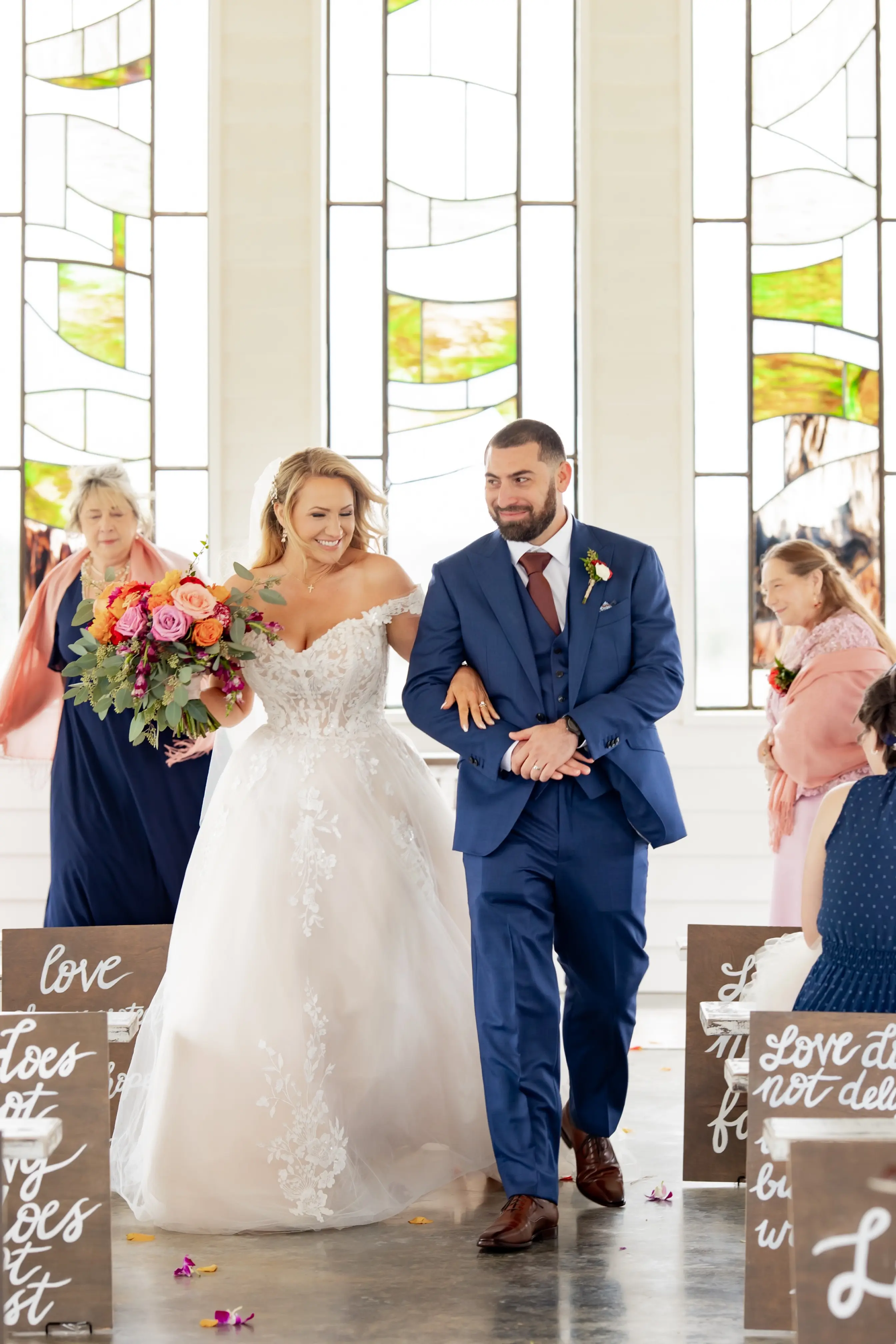 Bride wearing Harlem by Maggie Sottero walking down the aisle with her husband