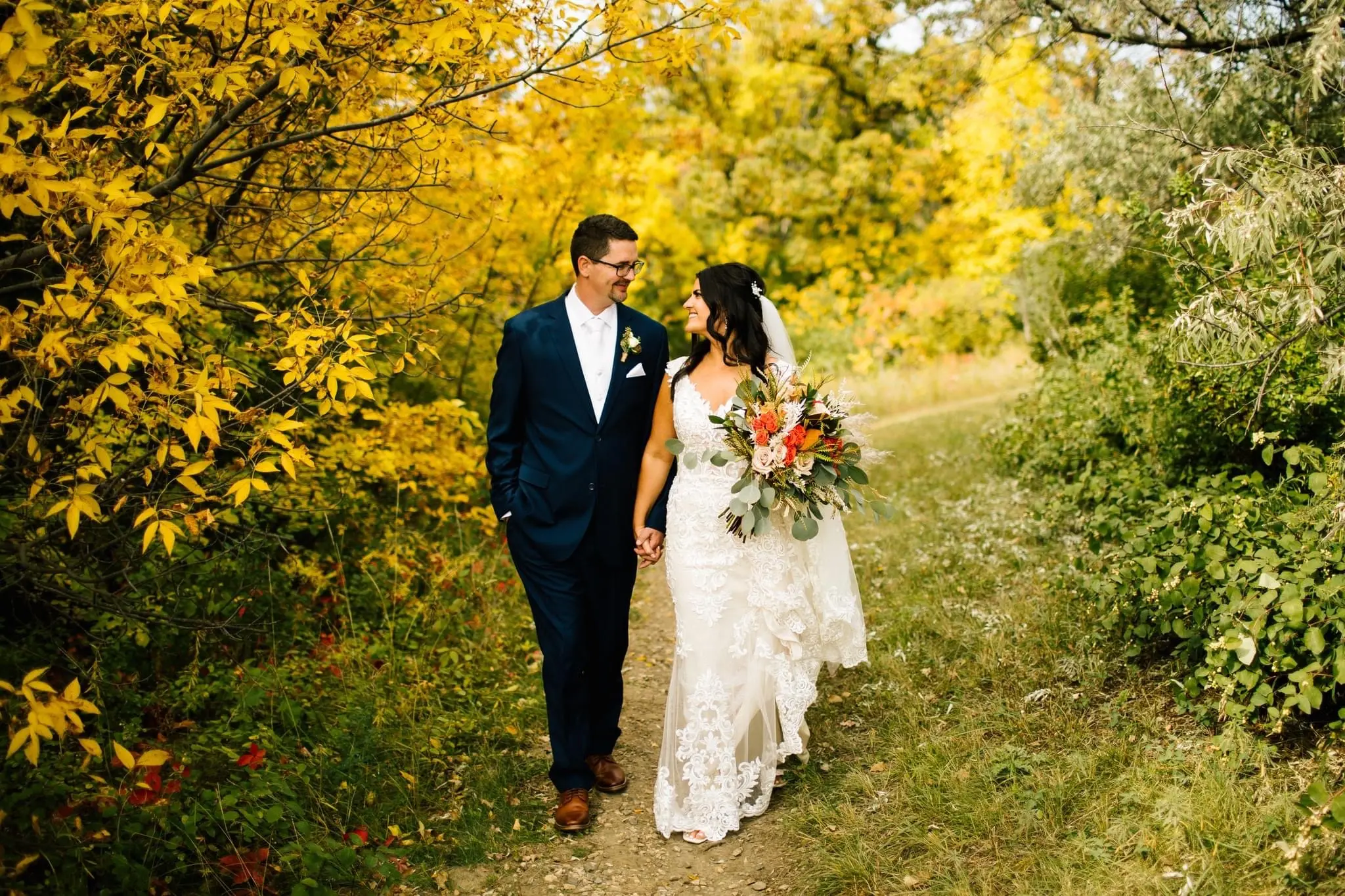 Bride Wearing Romantic Lace Wedding Gown Called Edison By Maggie Sottero Walking Through A Garden With The Groom