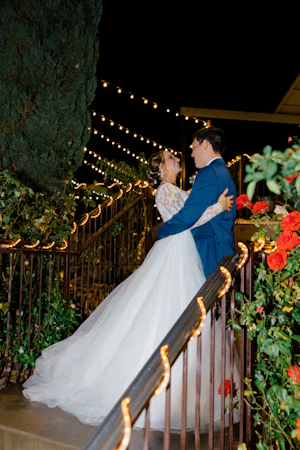 Groom and Bride Embrace. Bride in Romantic Long Sleeve Ball Gown Wedding Dress with Lace Motifs on Nude Bodice and Tulle Skirt Called Mallory Dawn by Maggie Sottero