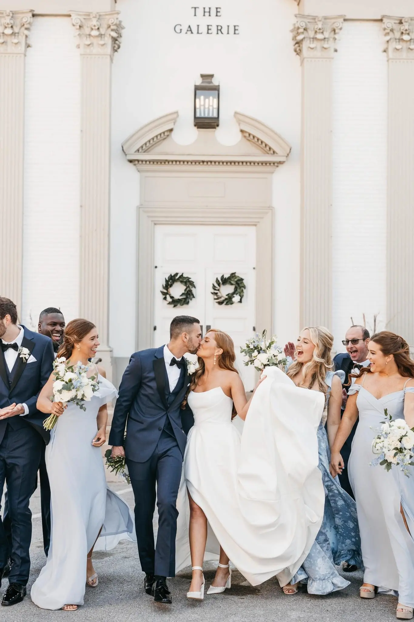 Bride wearing Aspen by Sottero and Midgley kissing her husband surrounded by their wedding party