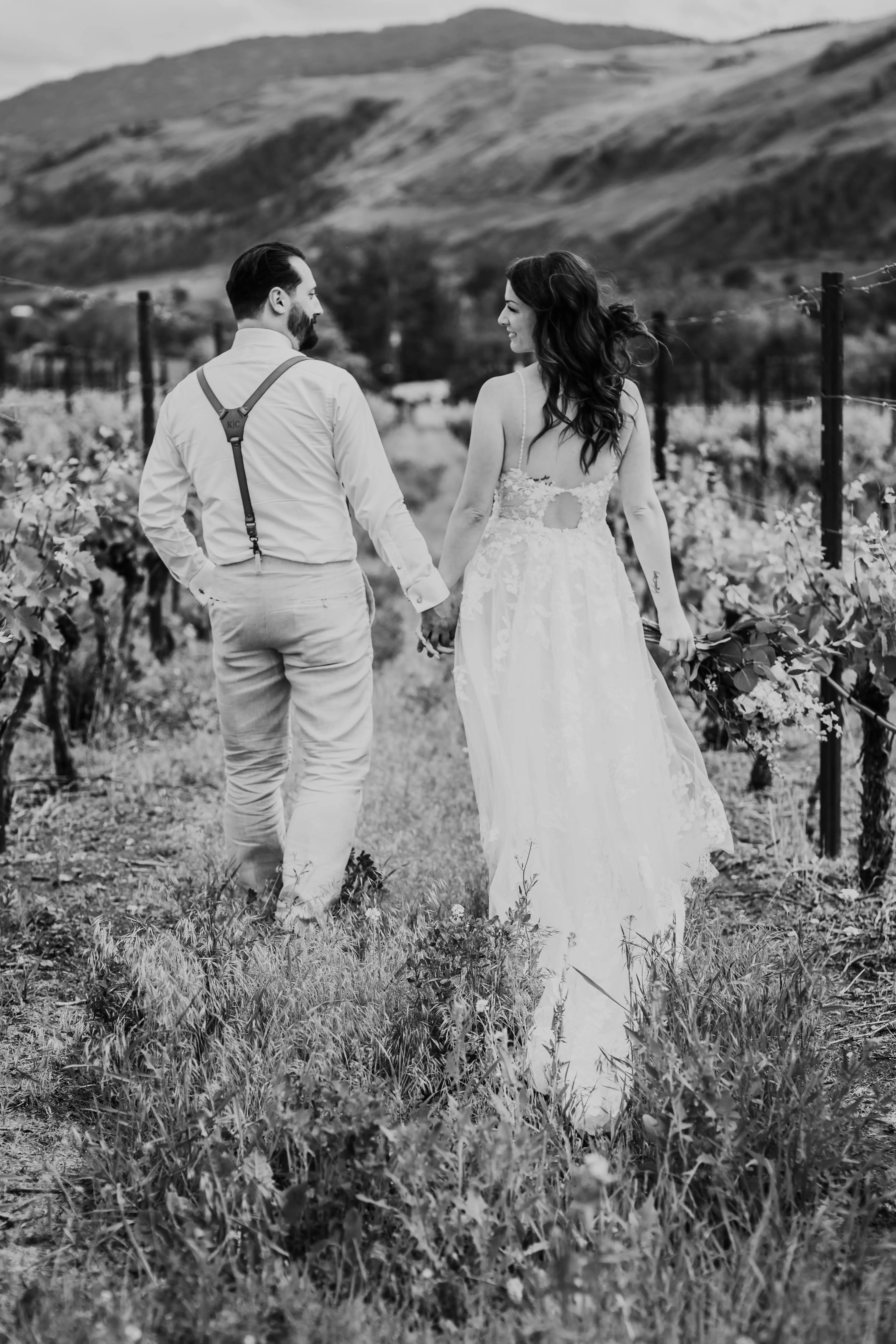Bride Wearing Romantic Key Hole Back A-Line Wedding Dress Called Marlow By Maggie Sottero Walking Away With Groom In A Vineyard