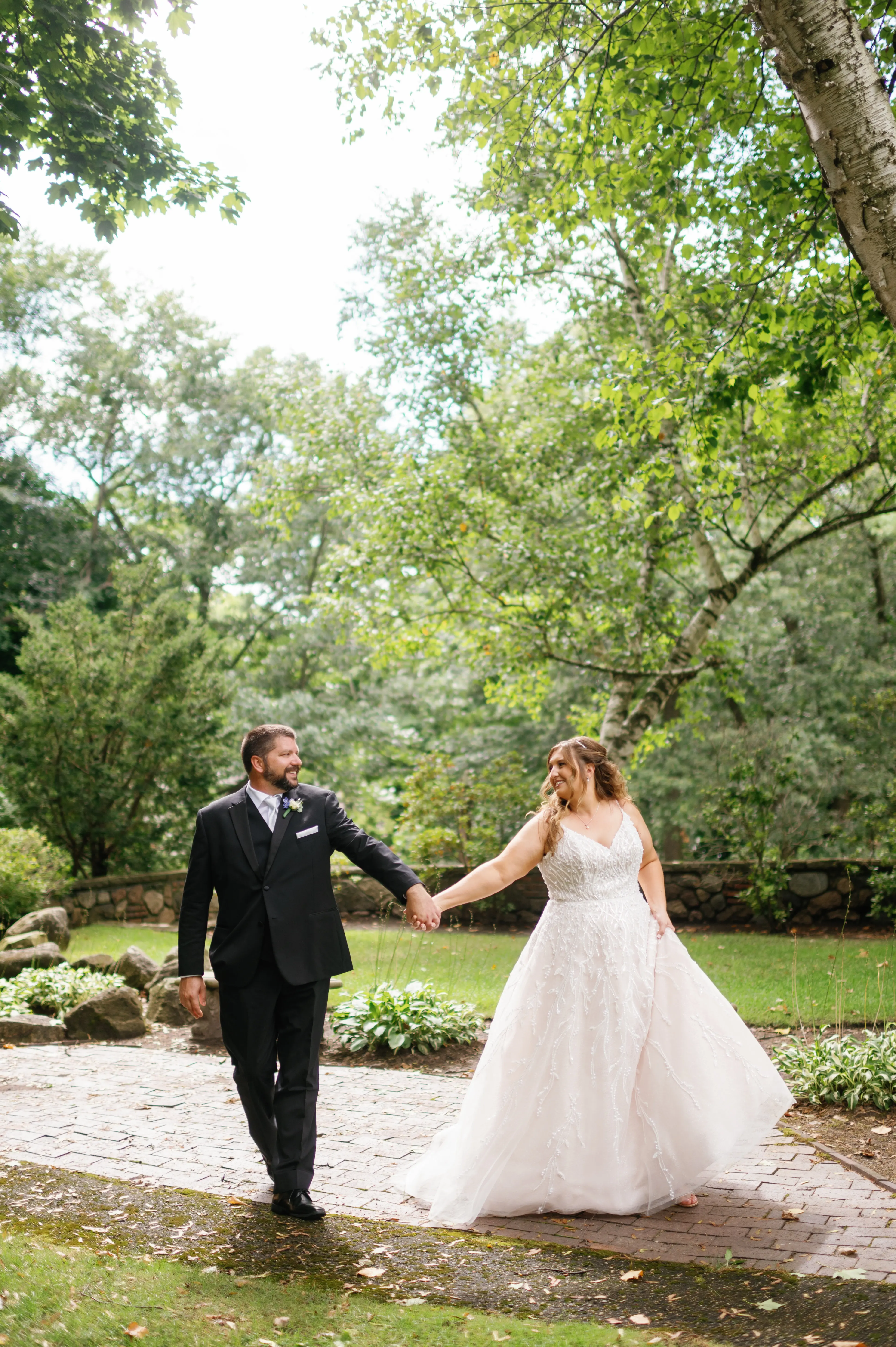 Bride Wearing Beaded Wedding Dress Called Marvine By Sottero And Midgley Holding Hands With Groom In A Garden