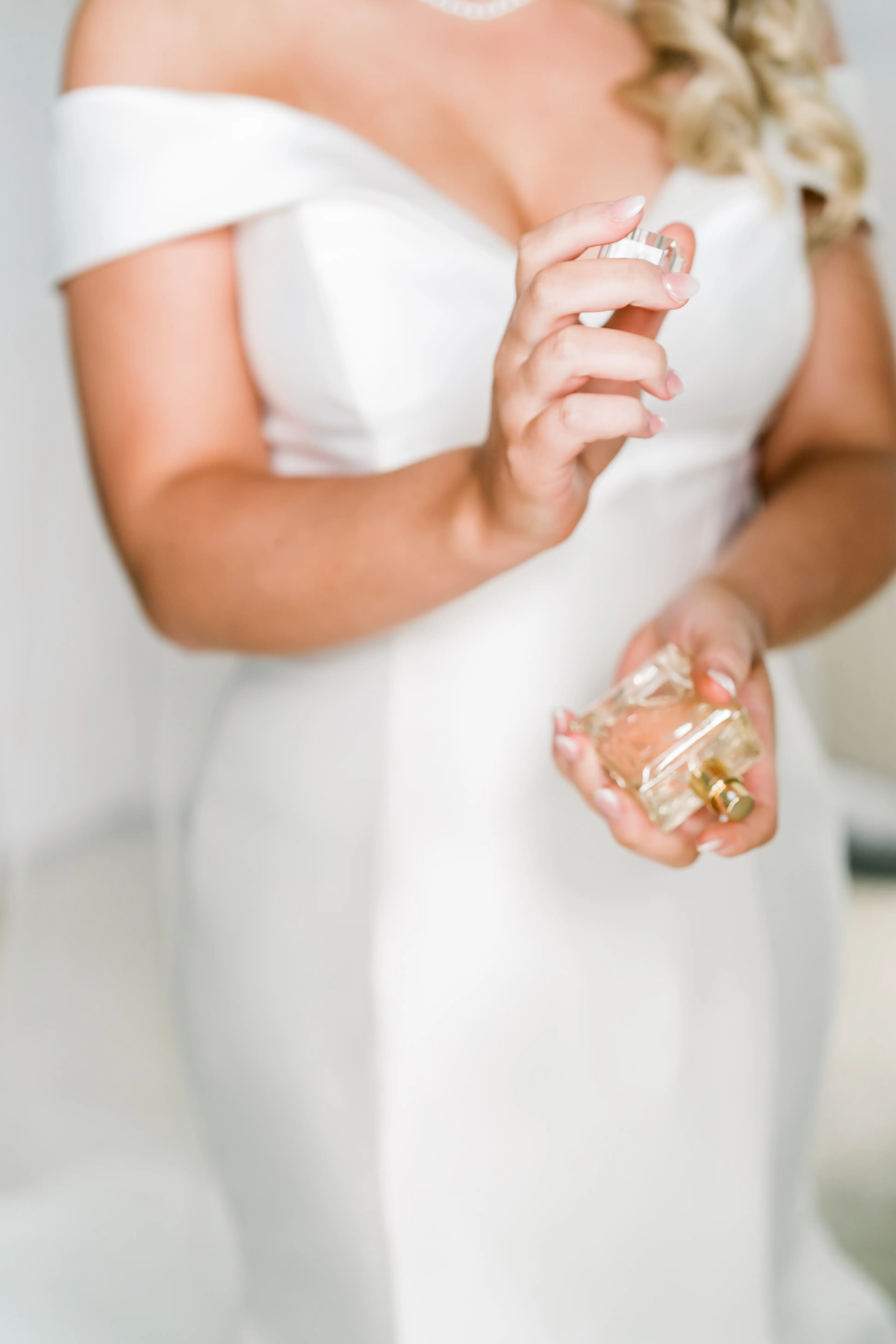Bride wearing Josie wedding dress by Rebecca Ingram spraying perfume on her wrists