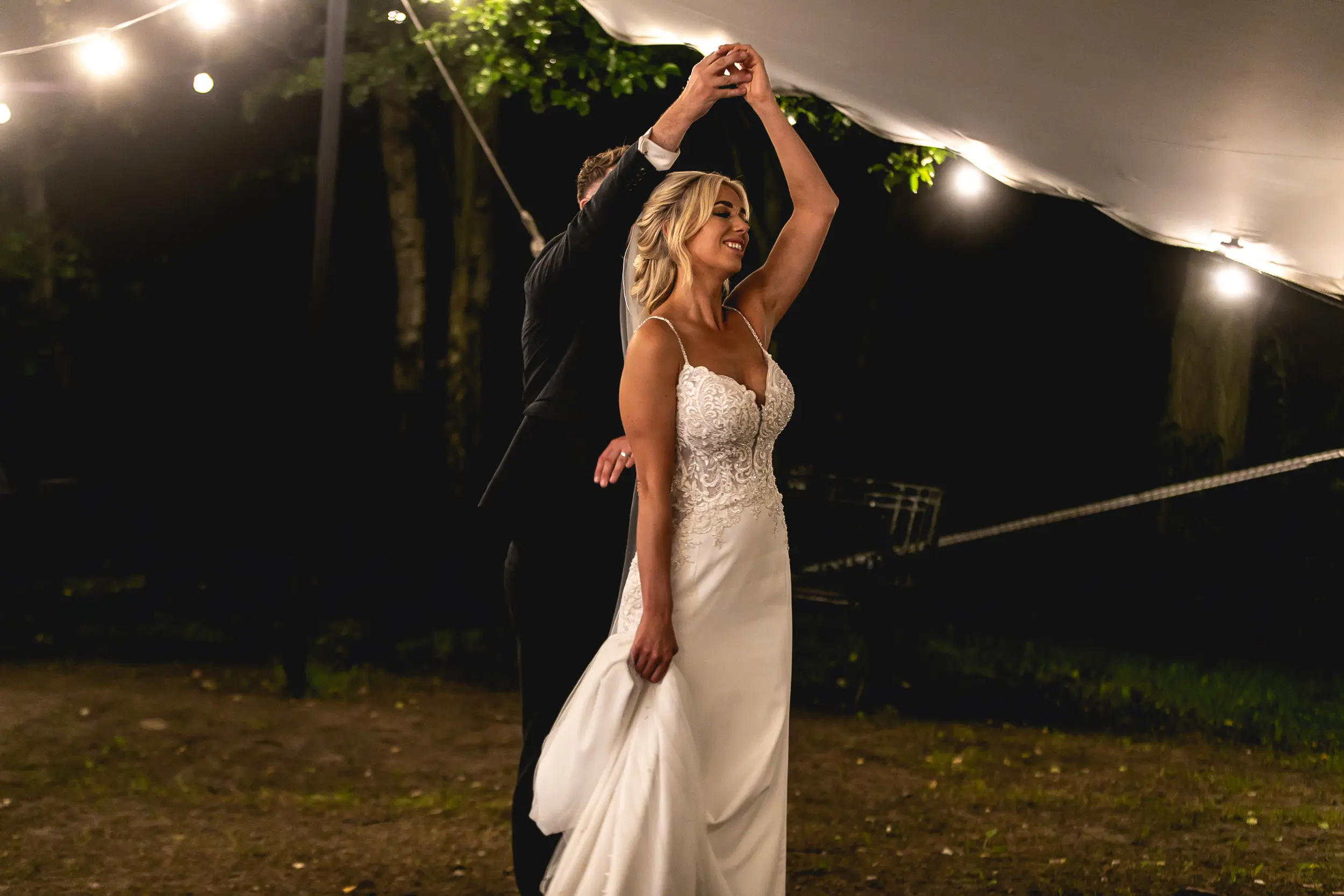 Bride and groom dancing under tent with sparkly fairylights.