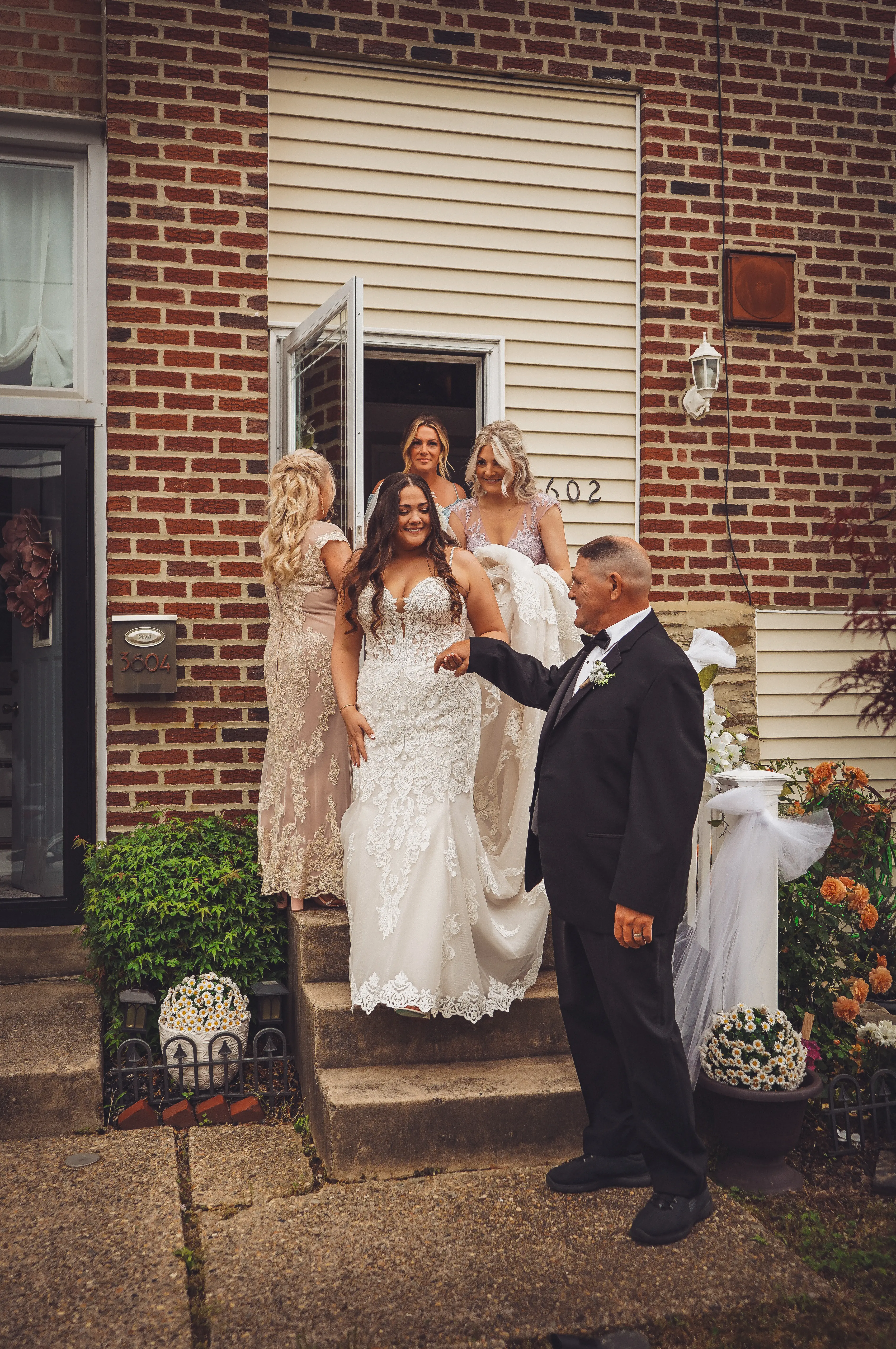 Bride wearing Fiona by Maggie Sottero walking out of her house with her bridal party
