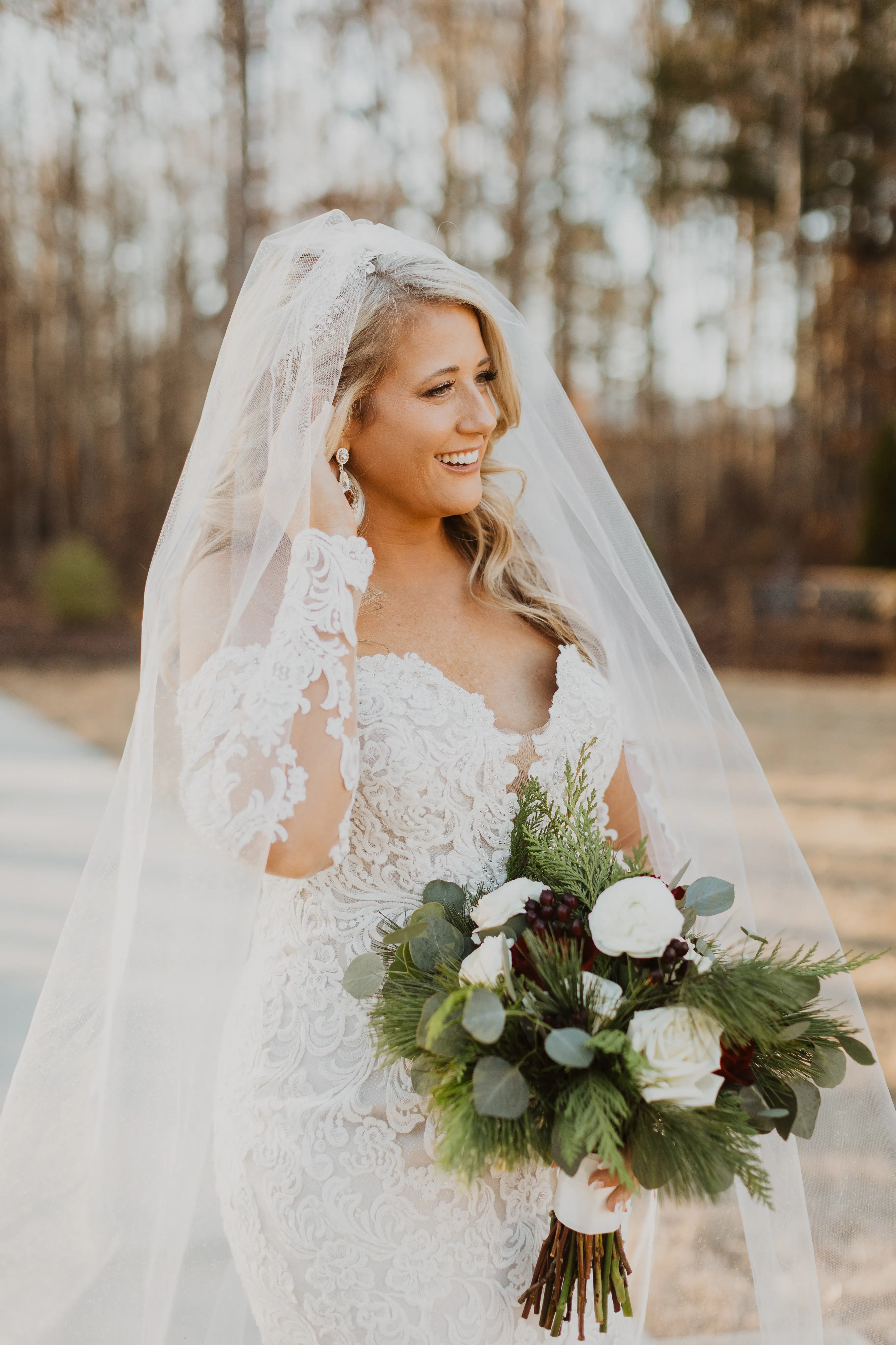 Bride In A Sparkly Lace Fit-And-Flare Wedding Dress Named Fiona By Maggie Sottero With A Long Veil And Flower Bouquet