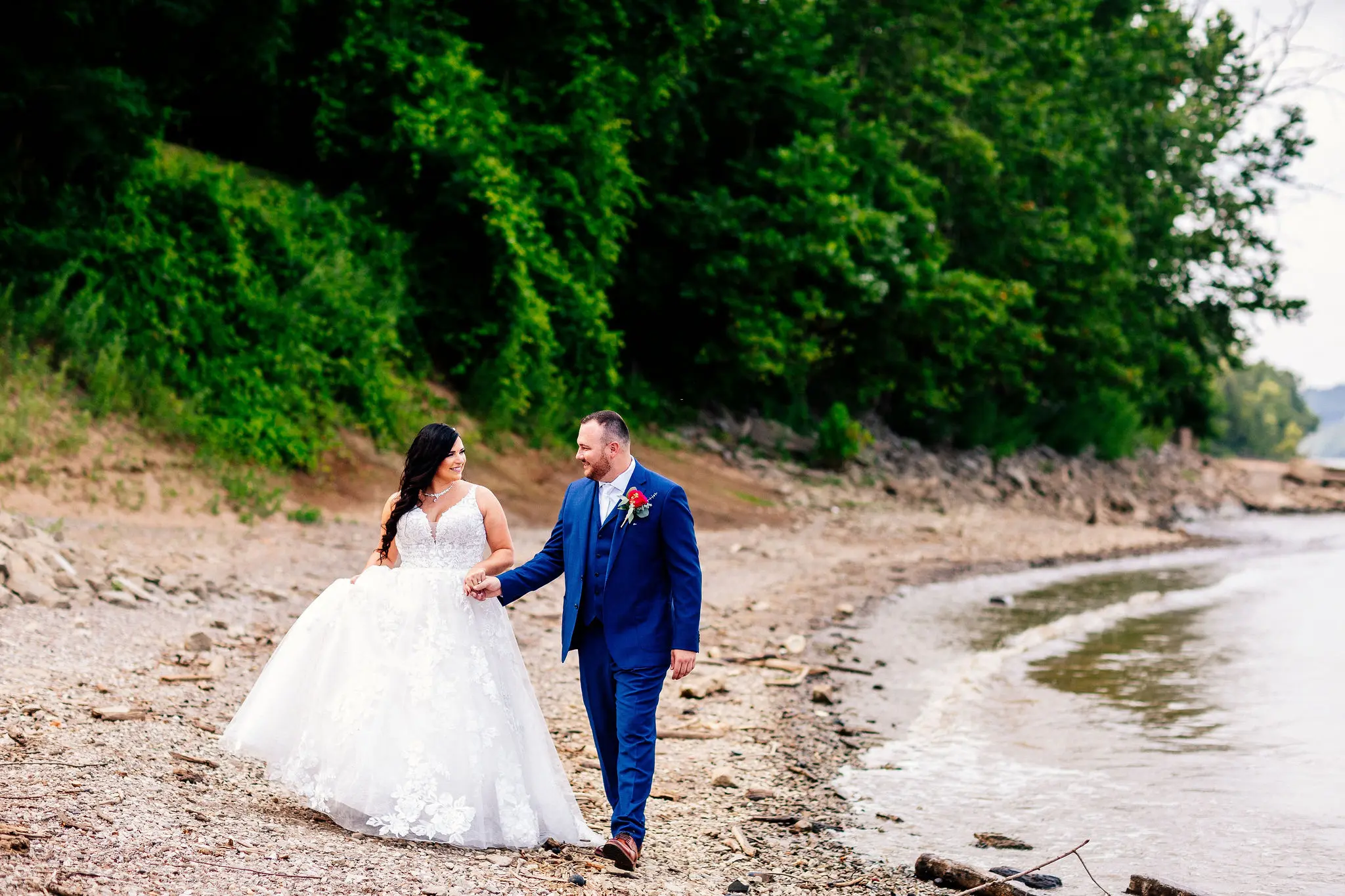 Newlyweds walking along the shoreline hand in hand.