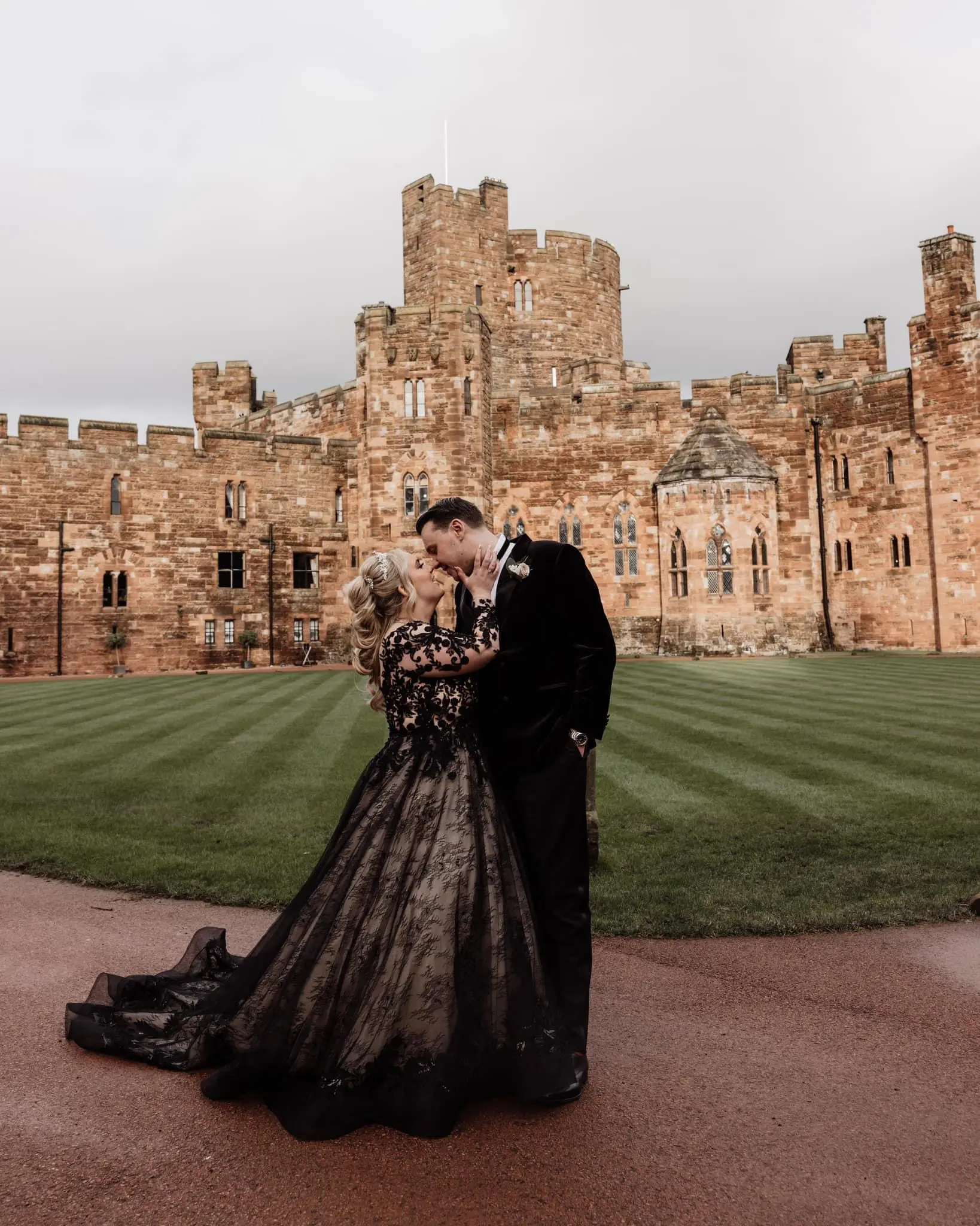 Bride Wearing Black Lace Ballgown Wedding Dress Called Zander By Sottero And Midgley Kissing Groom In Front Of A Castle
