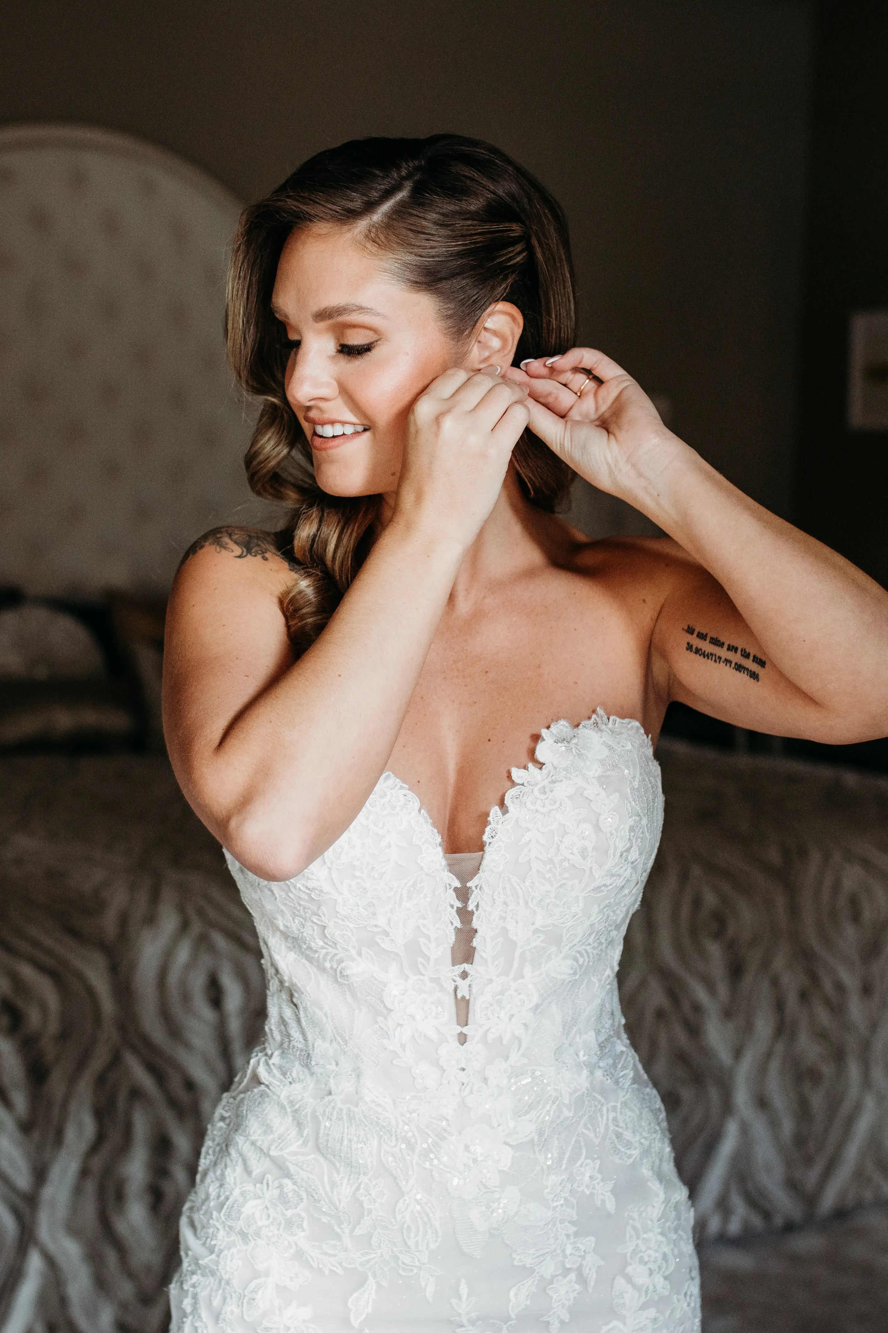 Bride Wearing Lace Mermaid Wedding Gown Called Montgomery By Sottero and Midgley Putting on Earrings