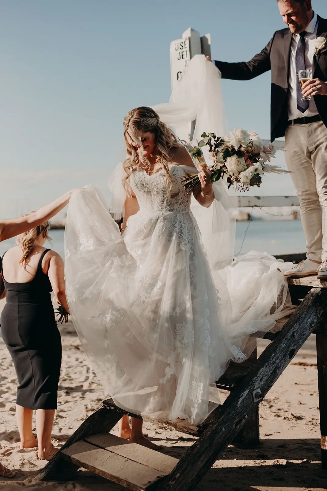 Bride Wearing Off-The-Shoulder Lace Wedding Dress Called Carson By Sottero And Midgley Walking Down The Stairs To The Beach