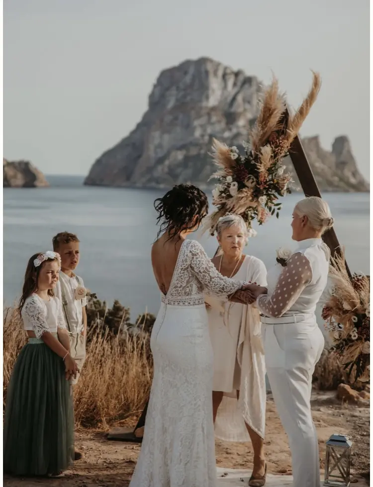 LGBTQ+ Brides At Beach Wedding With Bride In Open Back Long Sleeve Wedding Dress Called Drita By Sottero And Midgley