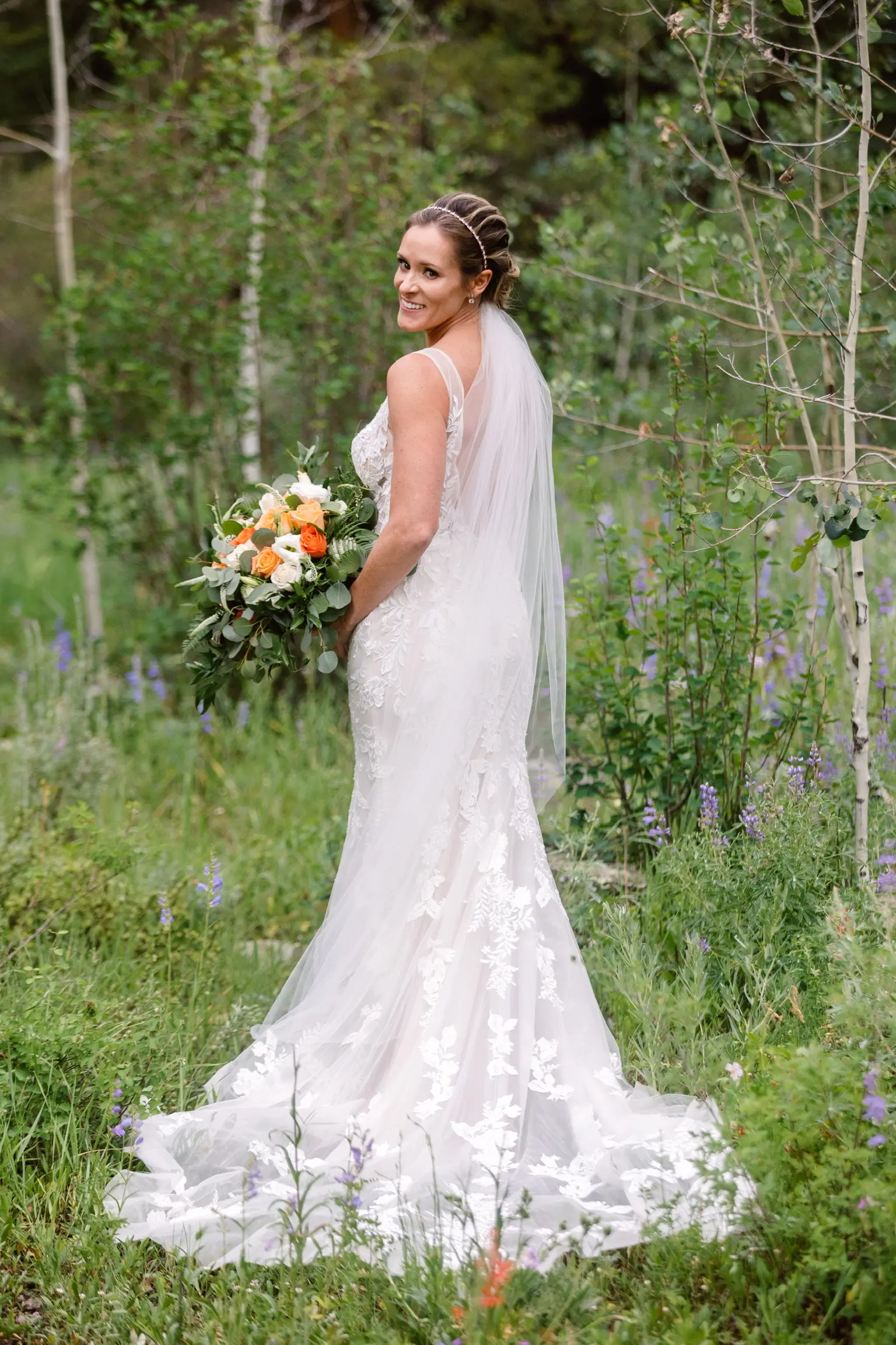 Bride holding orange and ivory bouquet waring wedding dress called Greenley.