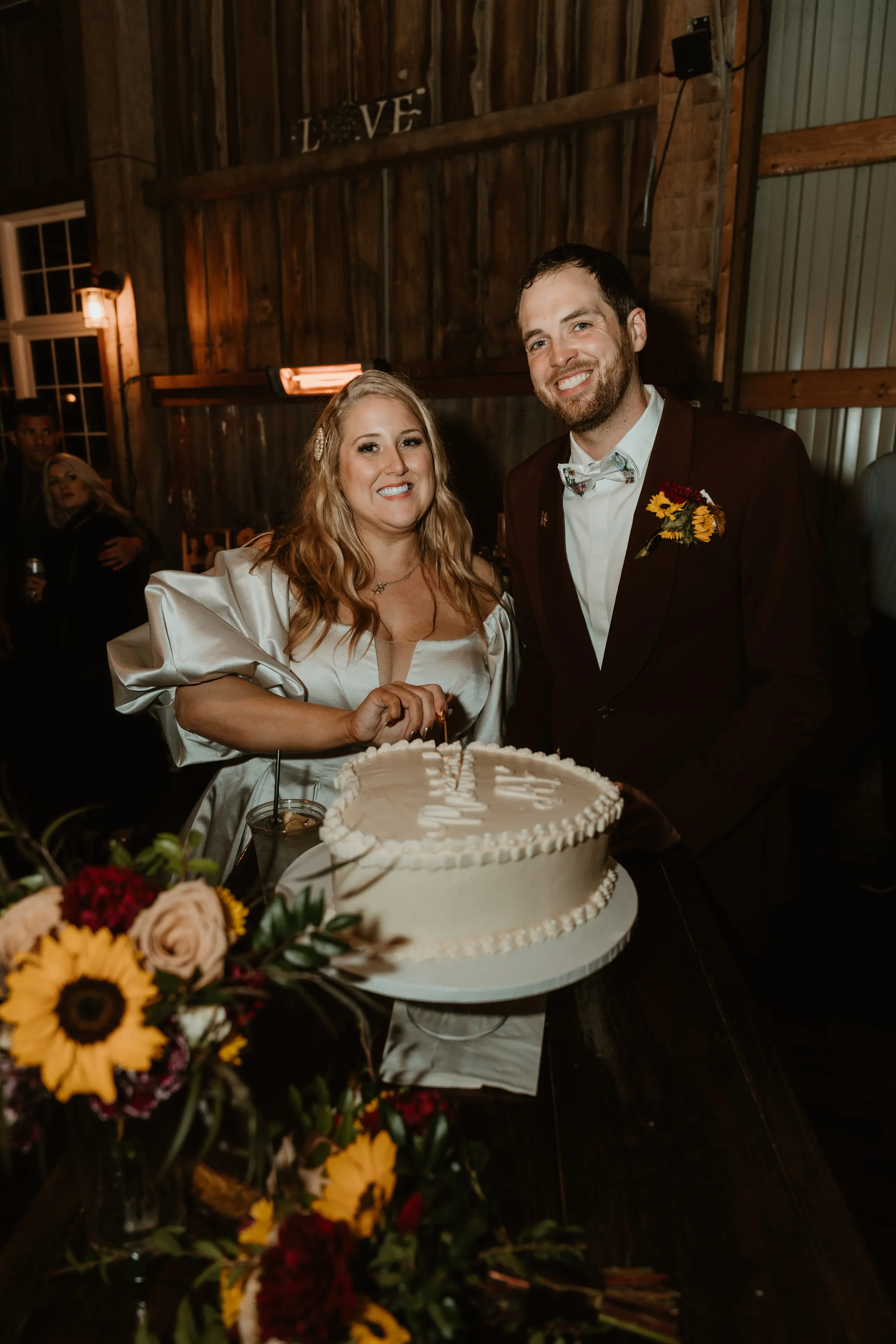 Bride wearing Juniper wedding dress by Sottero and Midgley cutting the cake with her husband