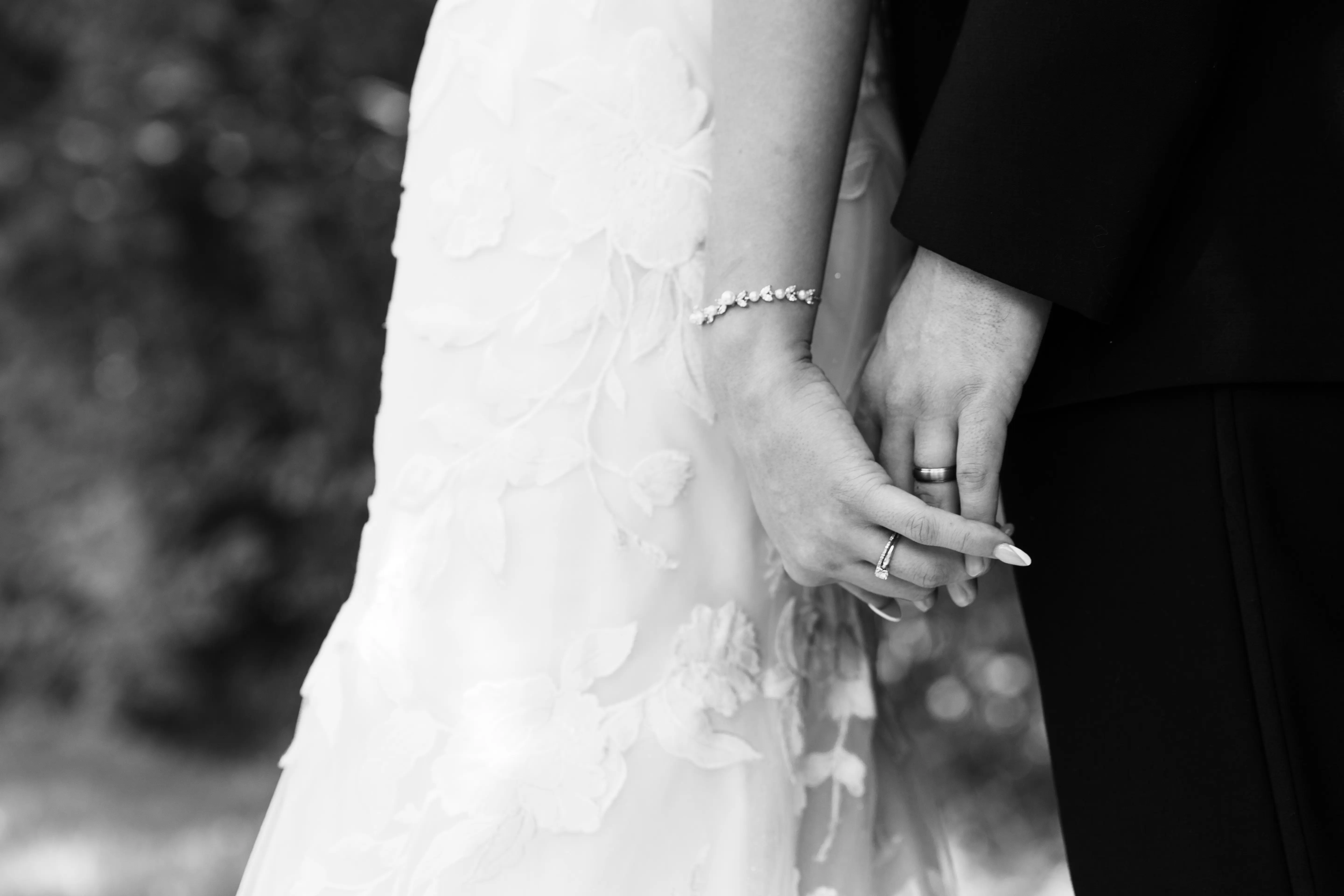 Newlyweds Holding Hands. Real Bride in Strapless Mermaid Bridal Gown with Oversized Floral Lace Motifs over Sparkle Tulle called Hattie by Rebecca Ingram